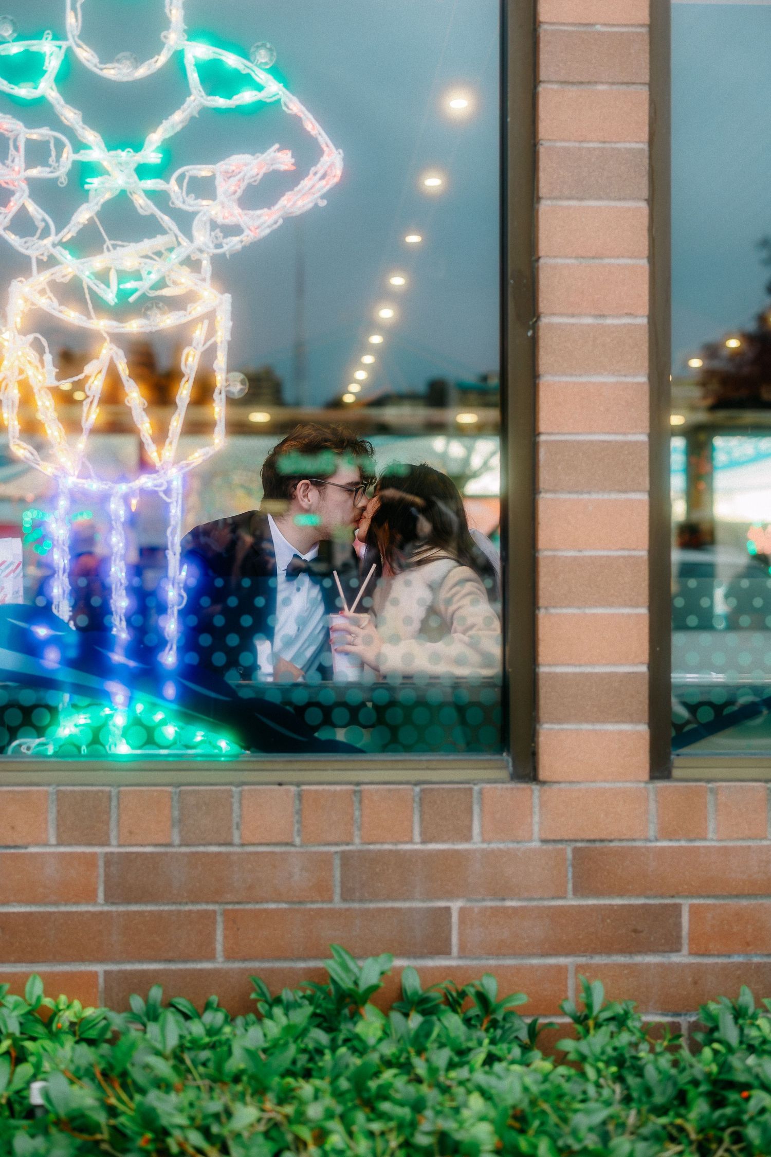 Colorful neon reindeer decorations illuminate a storefront window display at night.