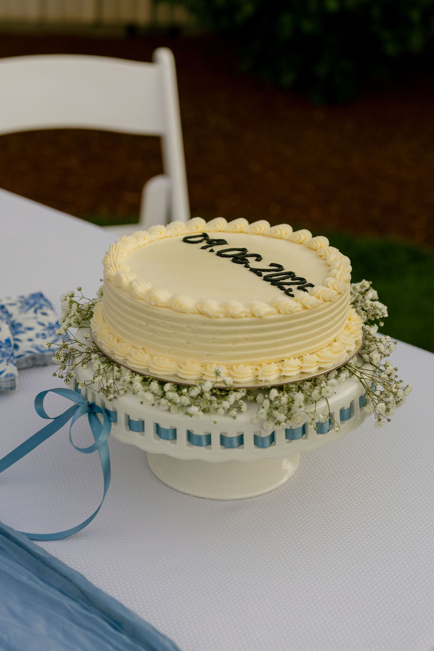 A white frosted wedding cake decorated with delicate baby's breath flowers and blue ribbons.