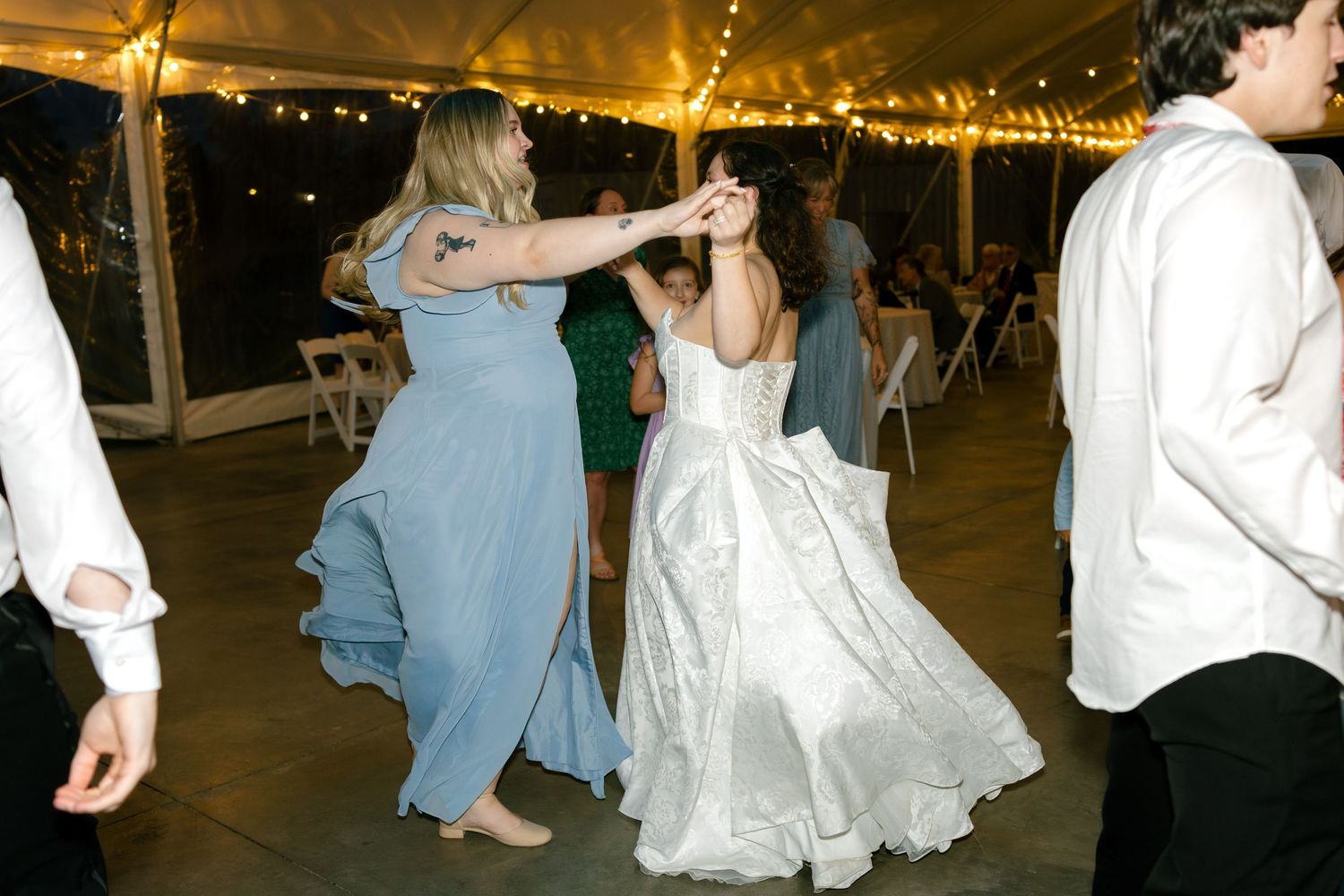Wedding guests dancing under warm lighting at an evening reception.