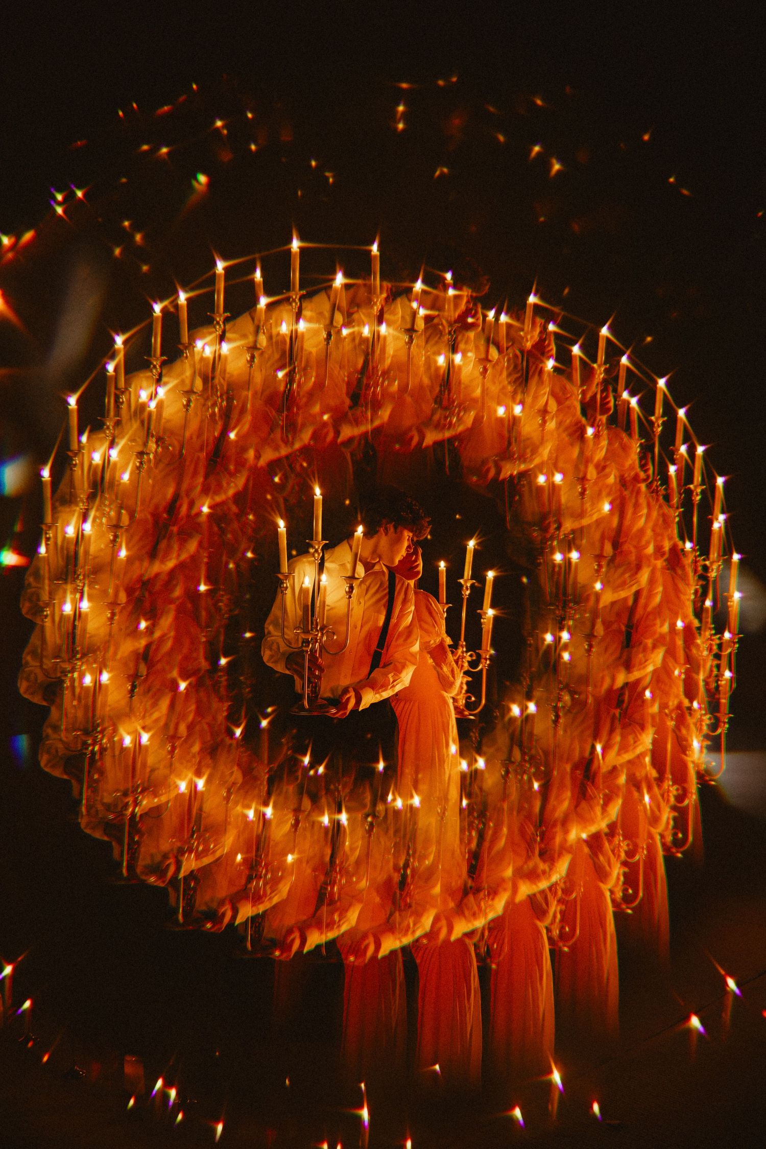Multiple candles arranged in a curved pattern create a warm glowing display against a dark background.