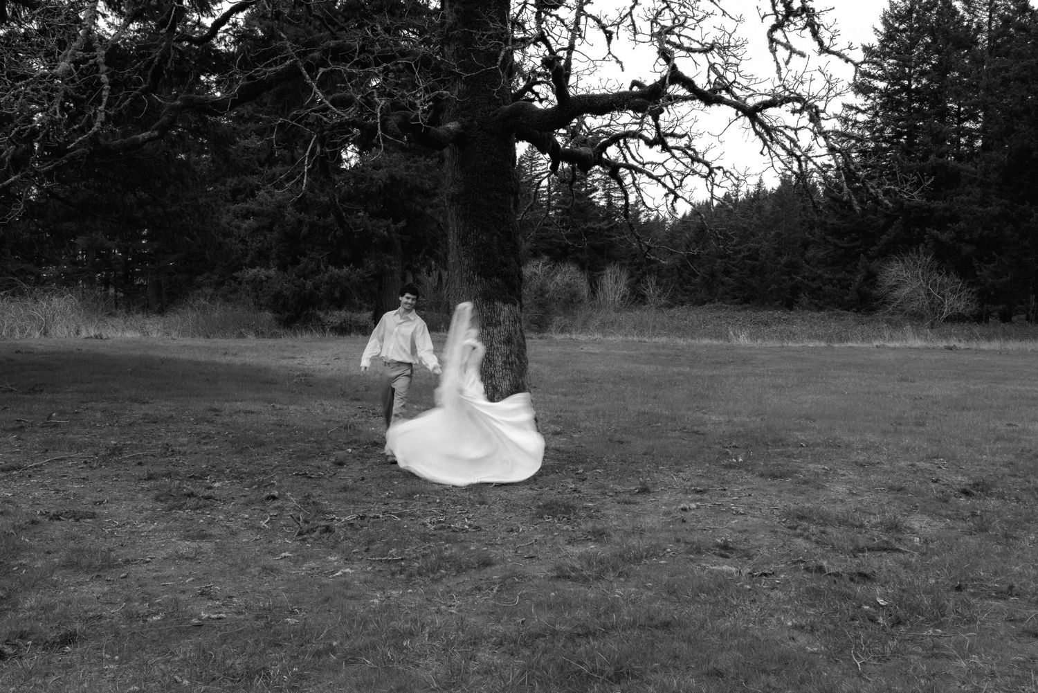 Black and white wedding photography capturing romantic moments in a meadow setting.