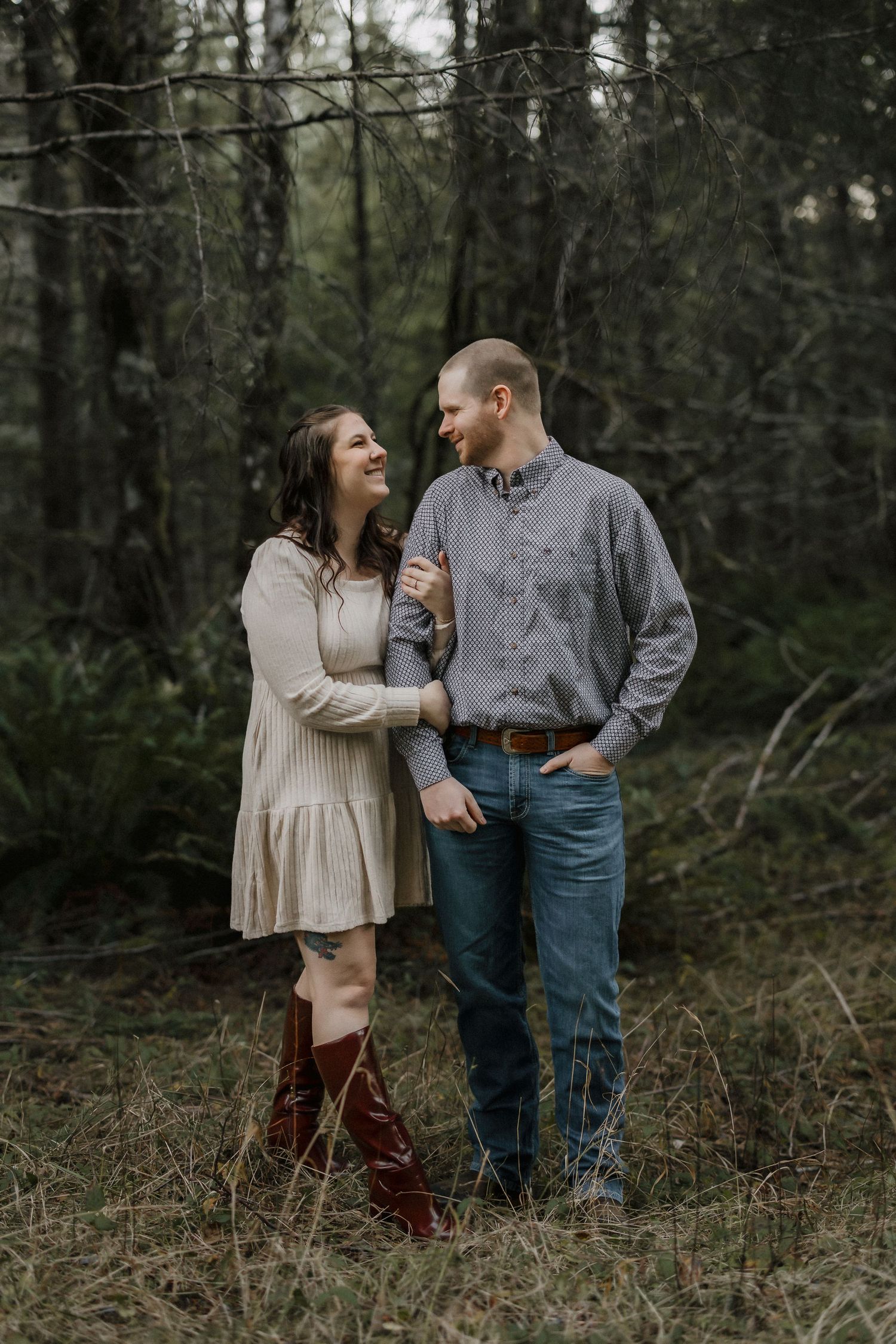 A couple shares joyful moments together during an outdoor photoshoot in a wooded setting.