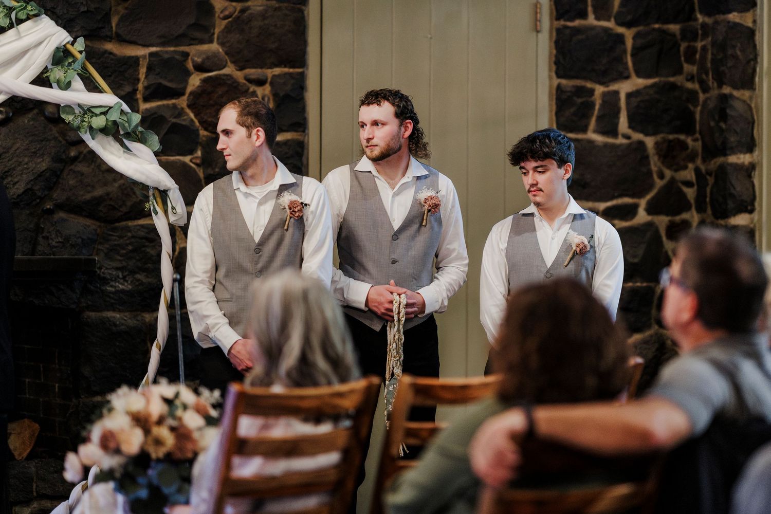 Stone-walled wedding venue decorated with white draping and elegant lighting for a ceremony.