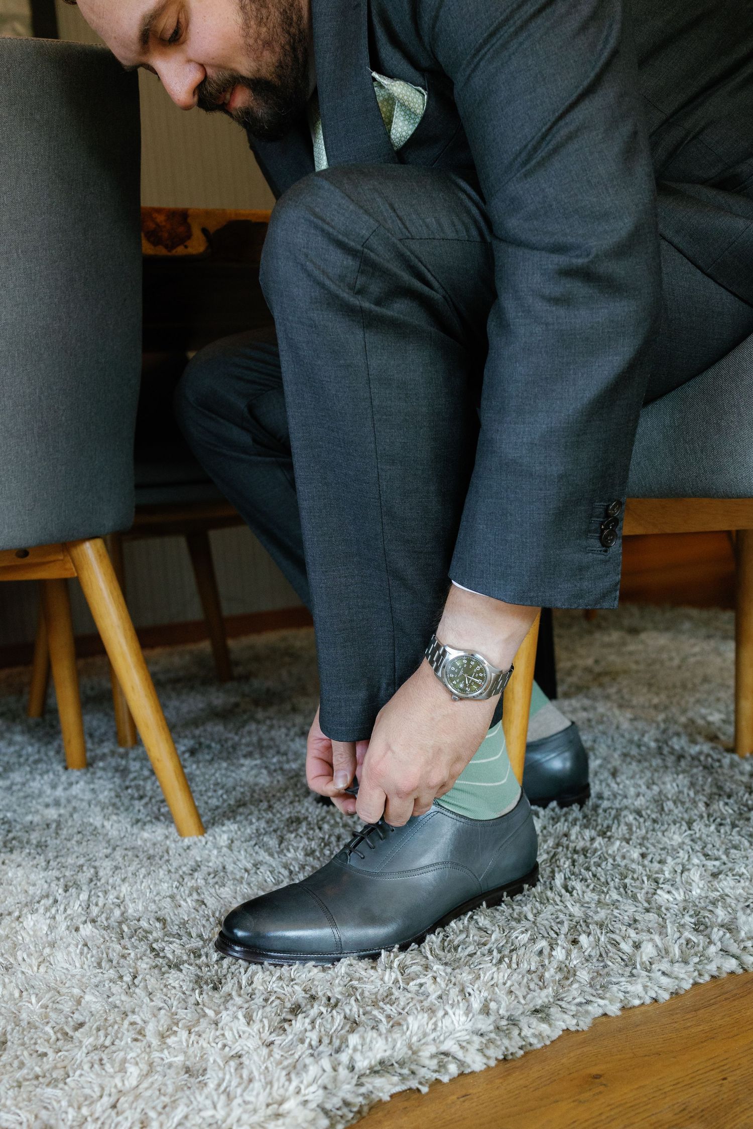 Close-up sequence showing a groom putting on formal black dress shoes while getting ready for the wedding.