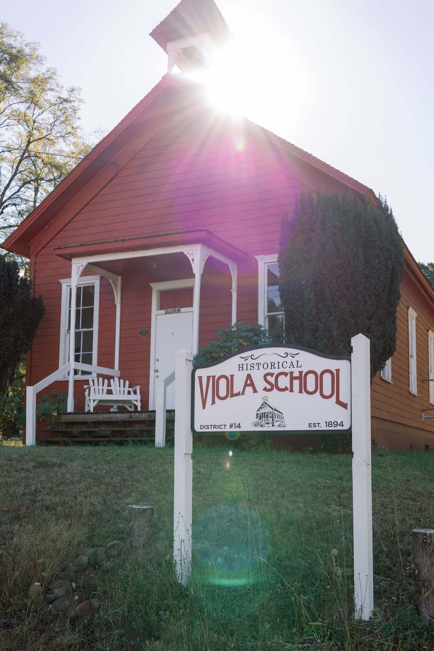 Historic red Viola School building with white trim and front porch captured in bright sunlight.