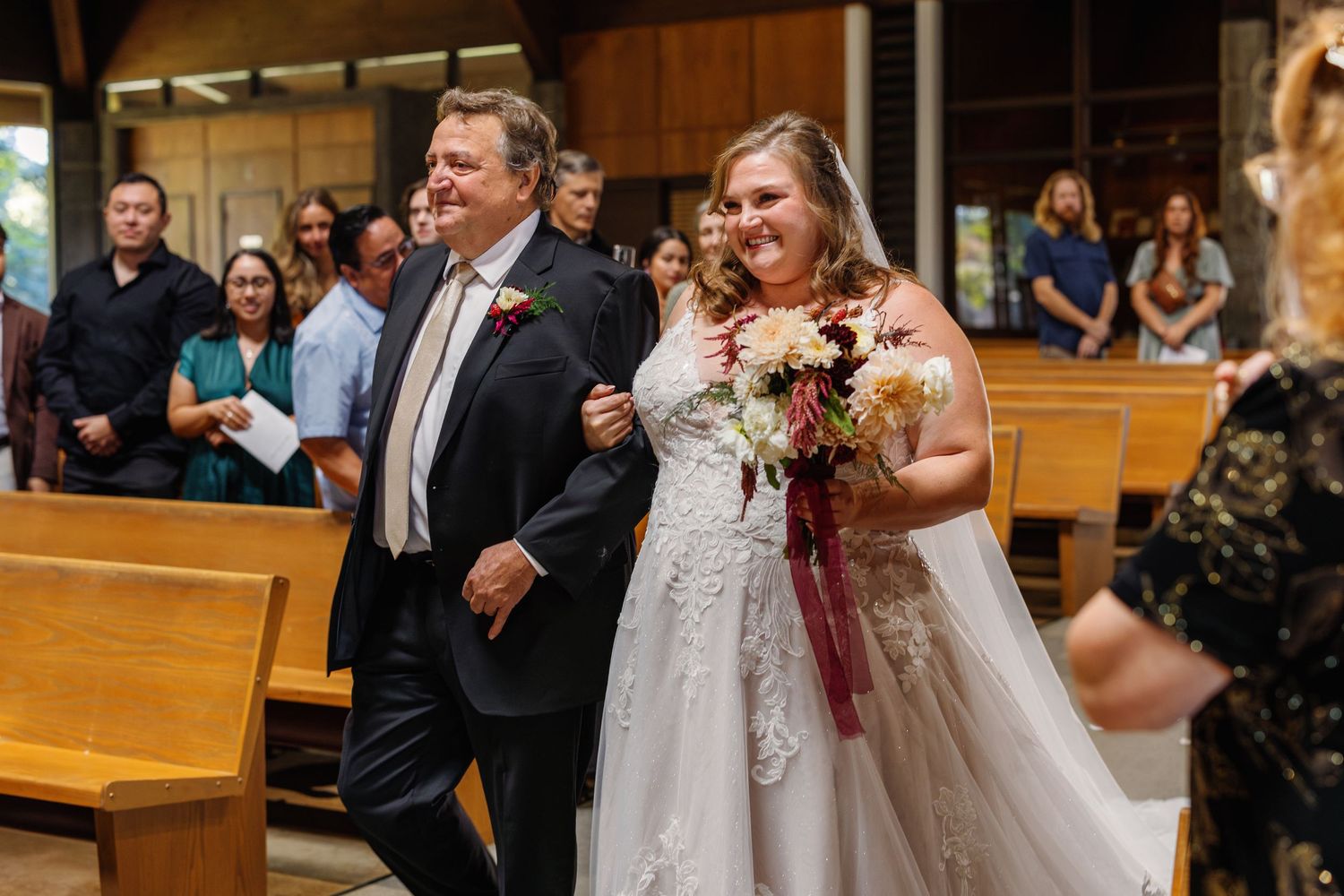 Wedding ceremony taking place in traditional church with wooden pews.