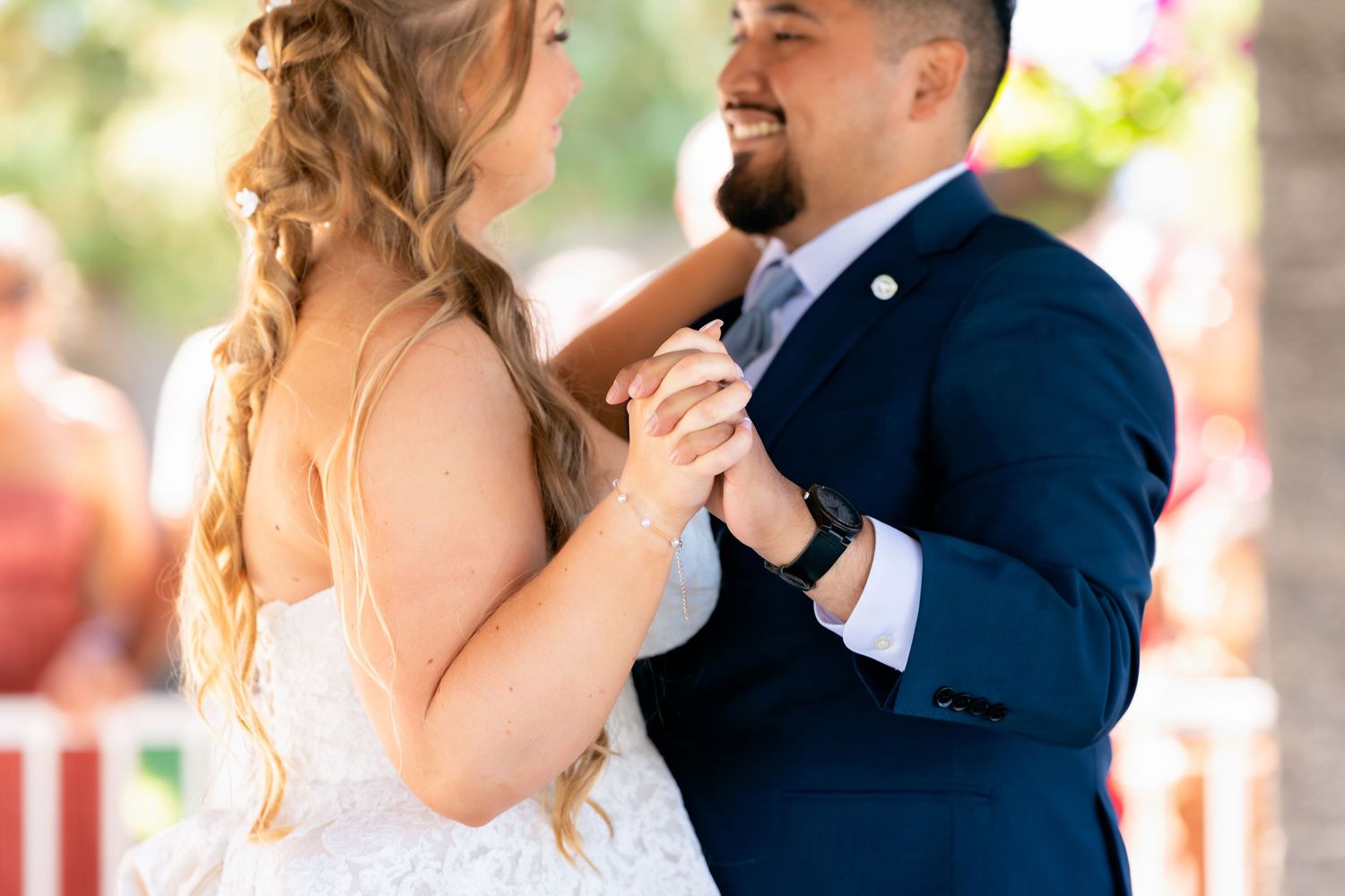 Bride and groom share their first dance smiling joyfully at outdoor wedding reception.