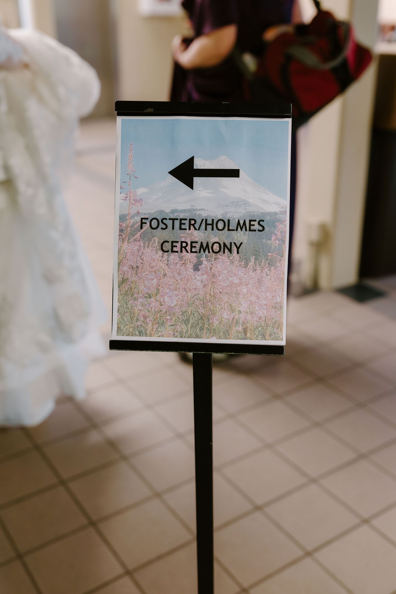 Foster Holmes wedding ceremony directional sign with mountain wildflower background on a stand.
