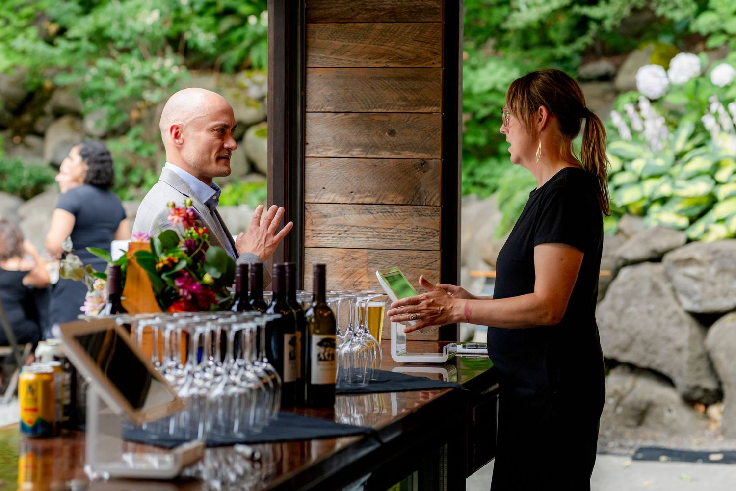 Man and bartender conversing at outdoor wedding bar.