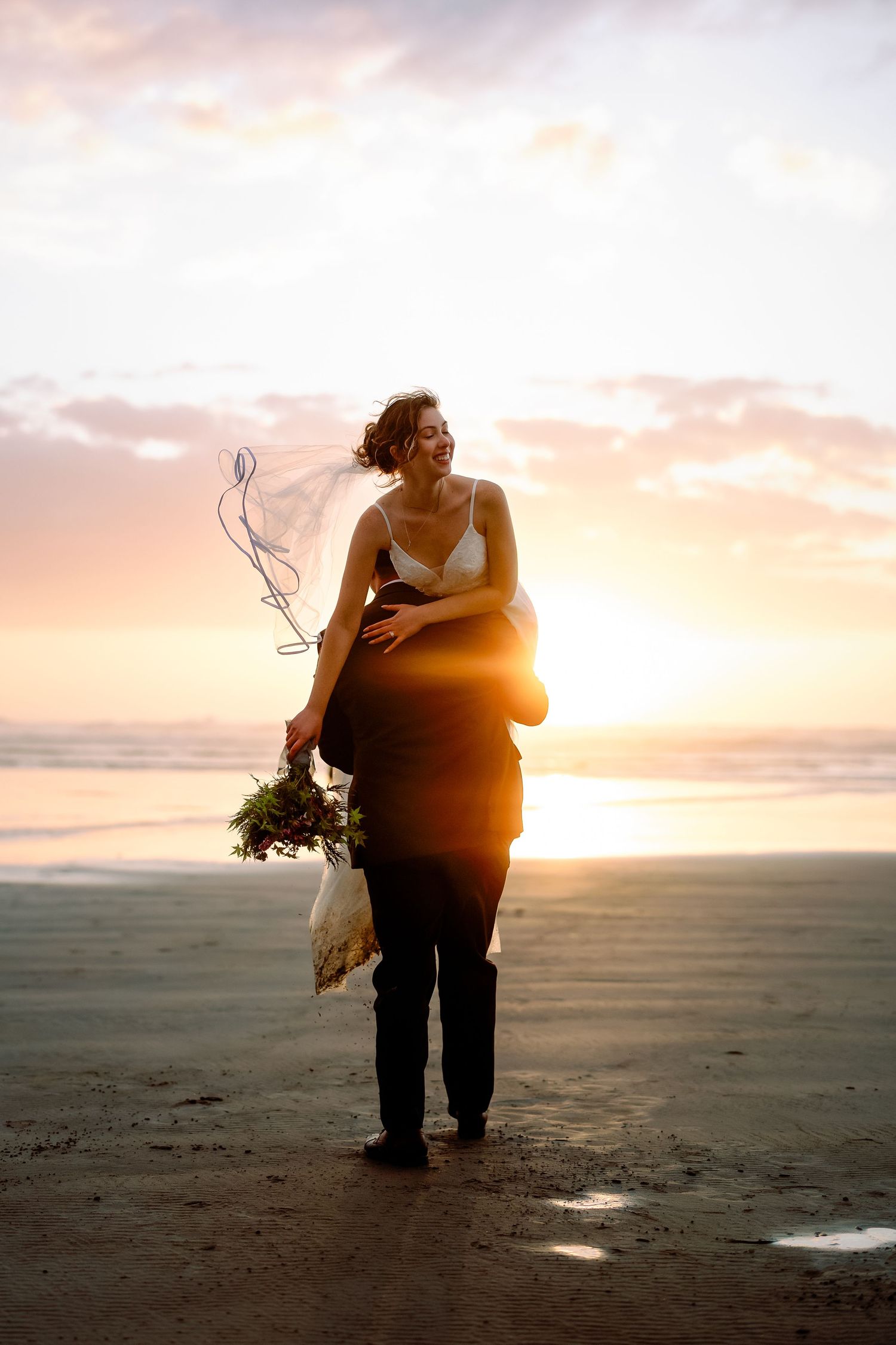 Silhouetted newlyweds share an intimate moment against a golden sunset on a deserted beach.