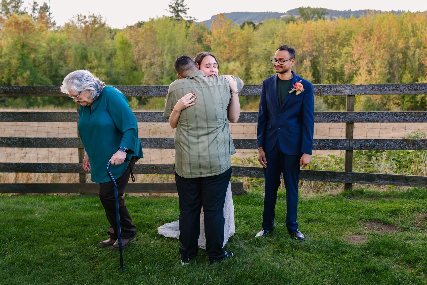 Group of people enjoying a candid moment together outdoors against a rustic wooden fence at sunset.