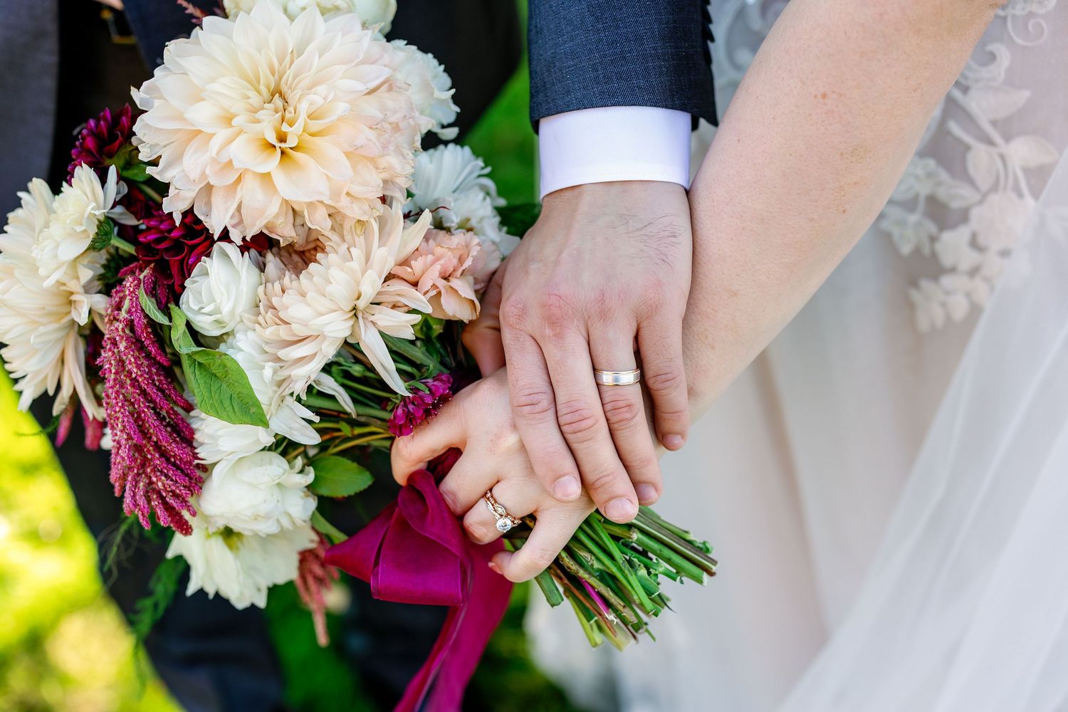 Wedding bouquet featuring peach dahlias and burgundy flowers with white accents against a dark background.