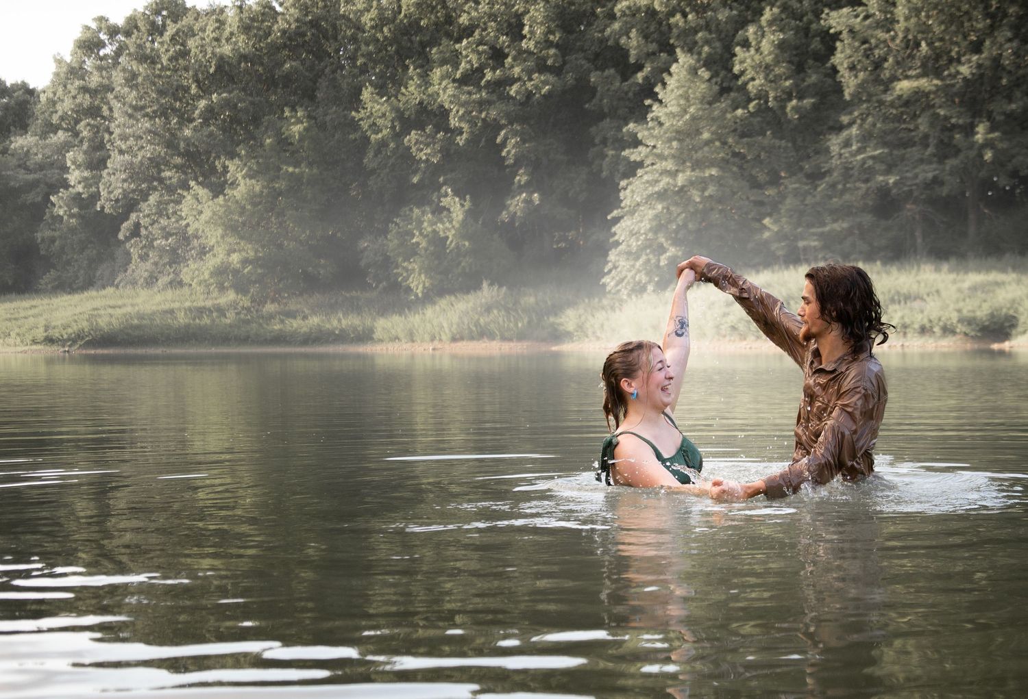 Parent and child playing together in lake water during summer.