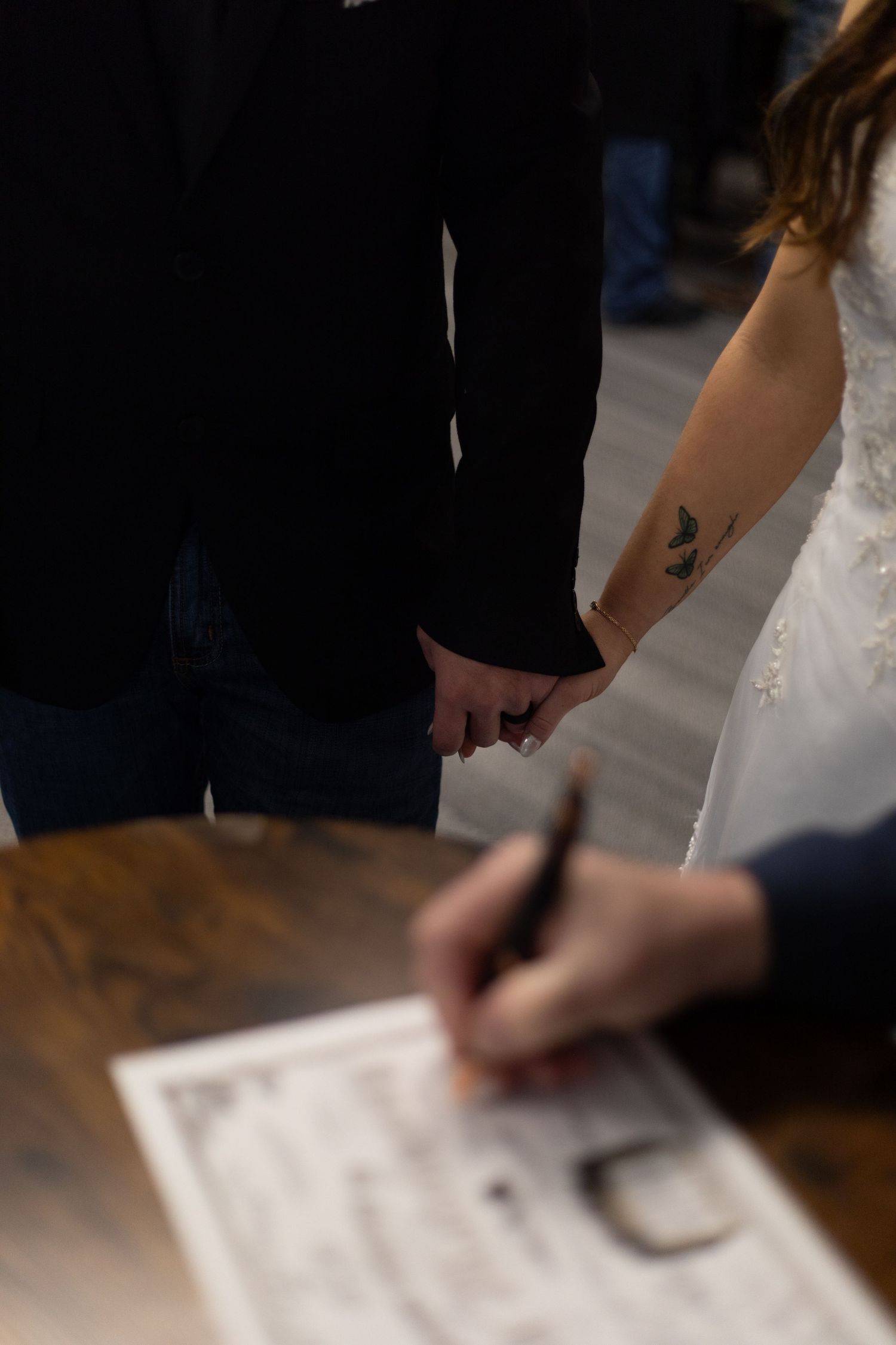A series of hands signing a document on a dark wooden surface in a sequence of close-up shots.