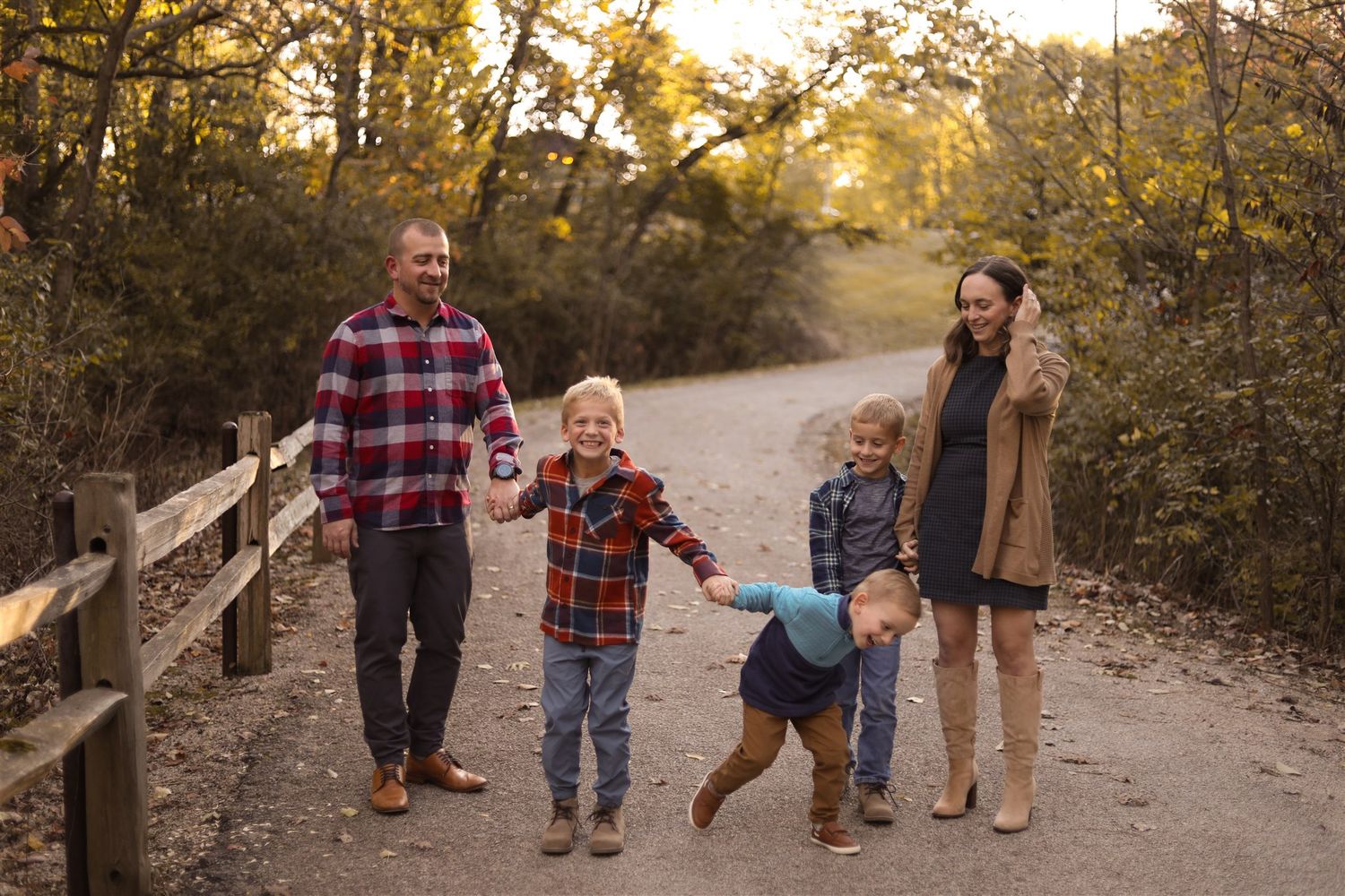 Family walking together on autumn trail wearing casual plaid shirts.