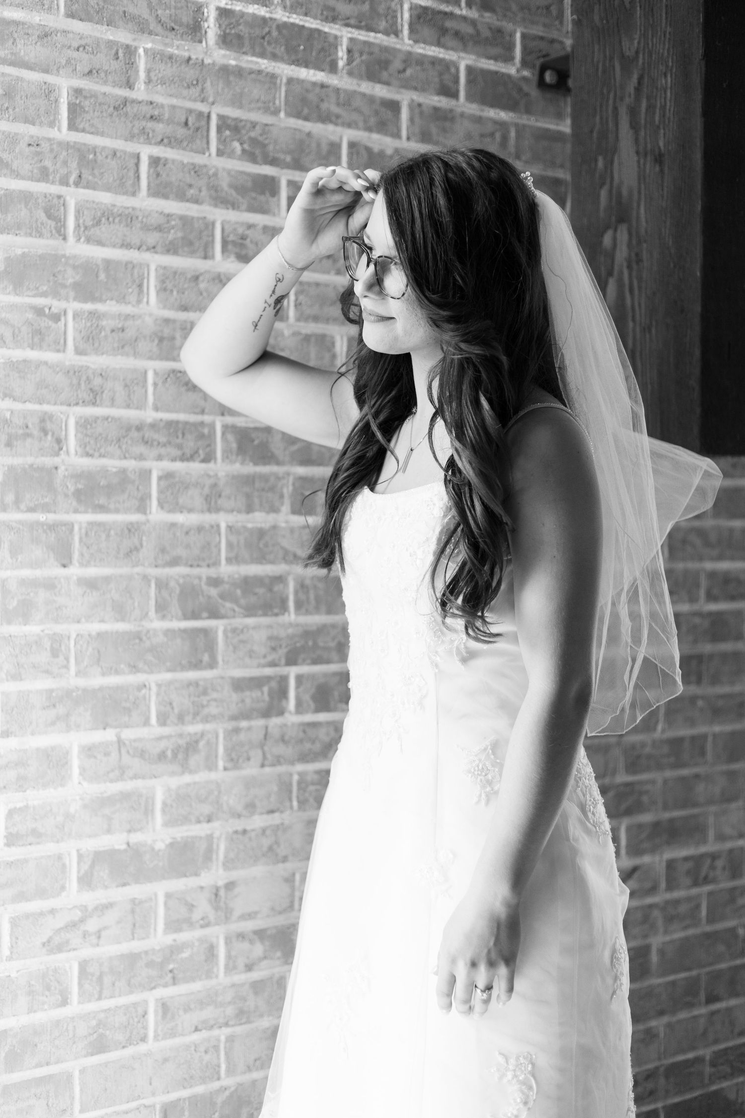 A black and white photo series showing a bride in a white wedding dress posing against a brick wall.