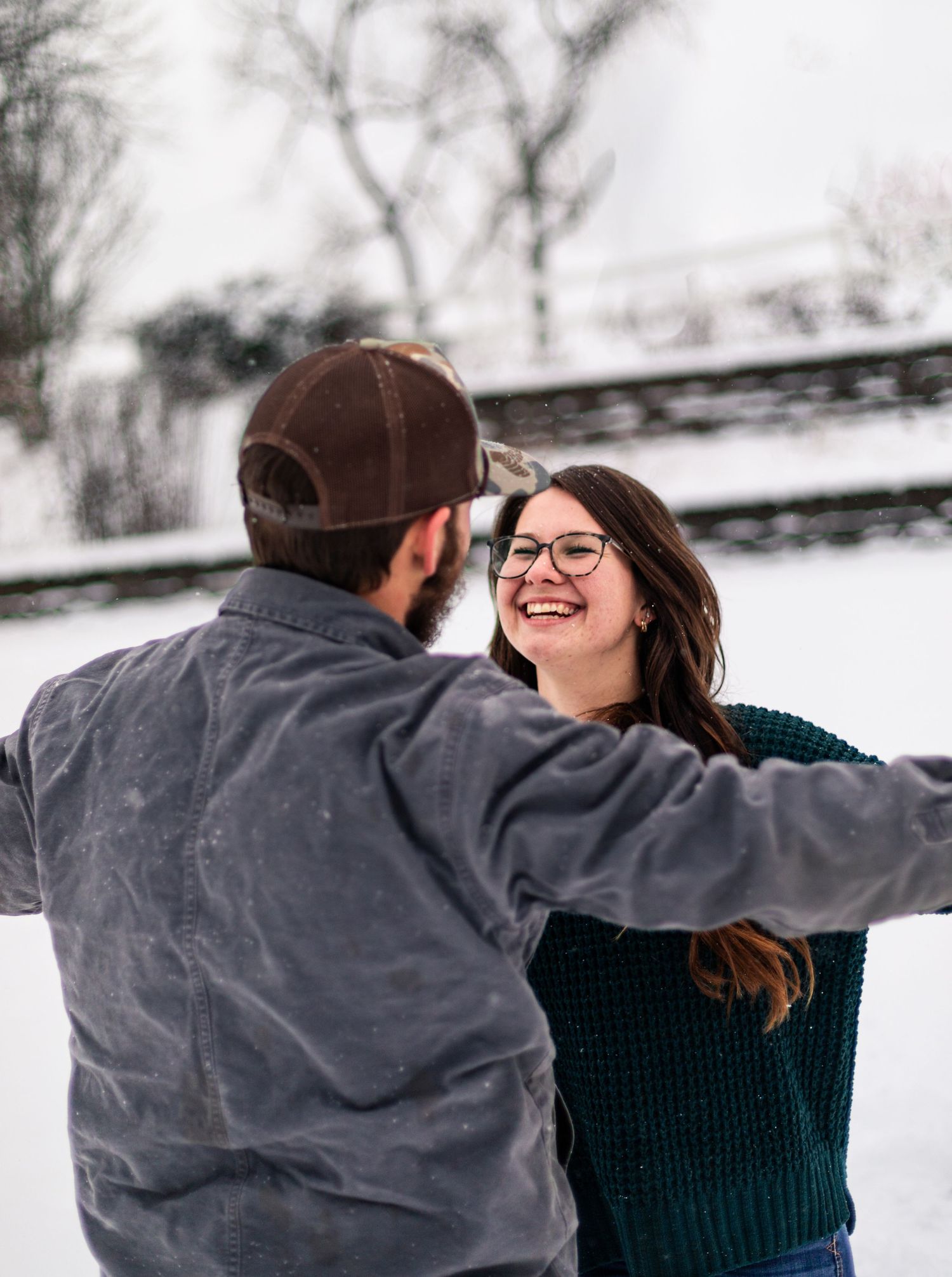 Joyful couple in winter clothing laughing together in the snow.