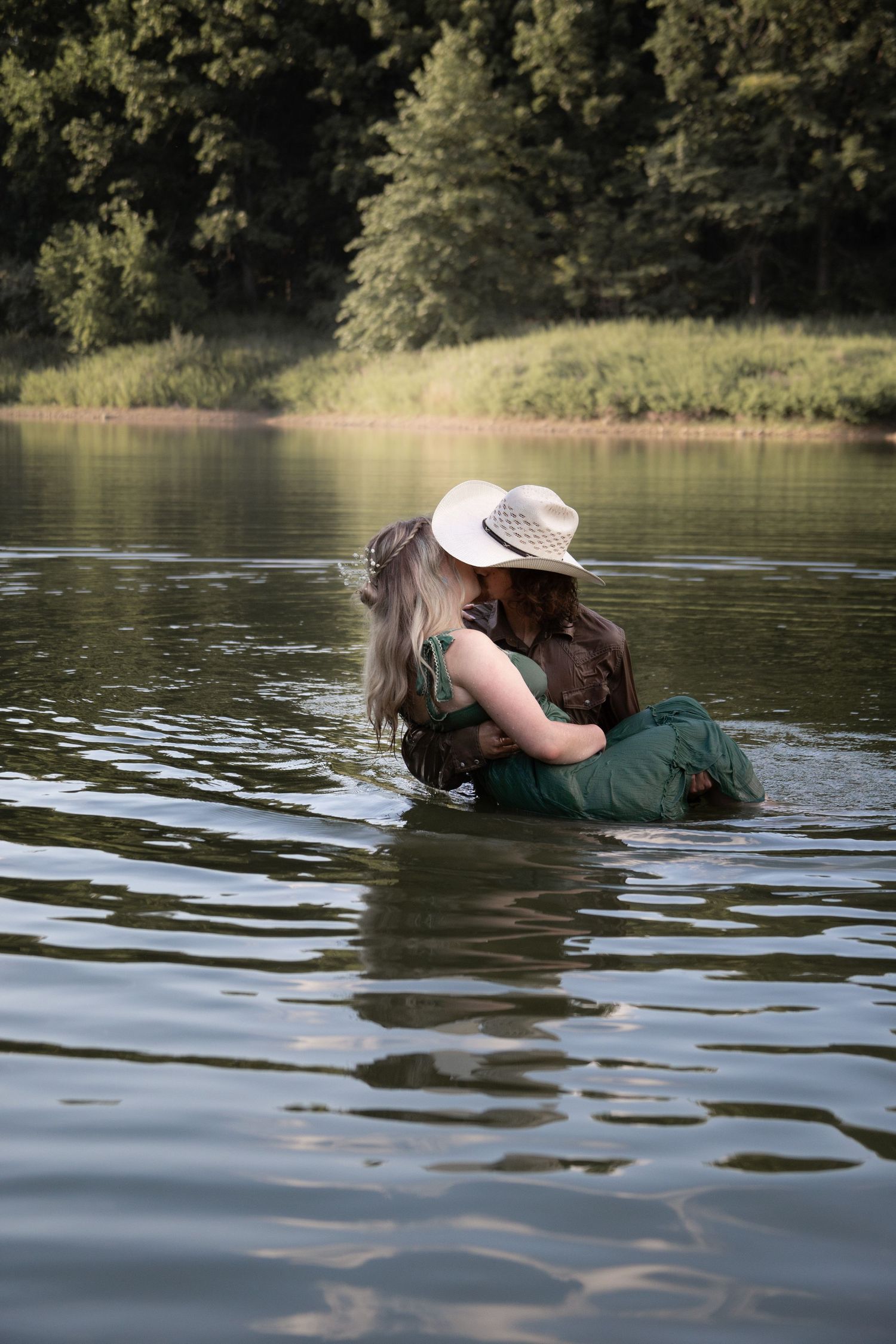 Two people share an intimate moment while floating in calm lake waters.