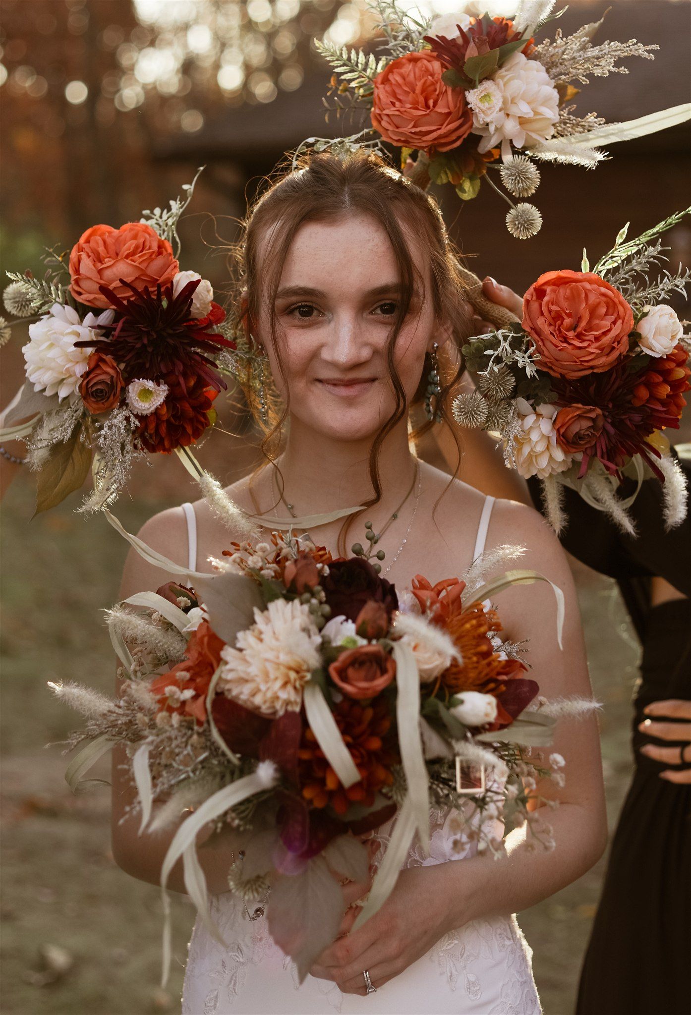 Beautiful autumn wedding bouquet with red and white flowers and dried elements in golden light.