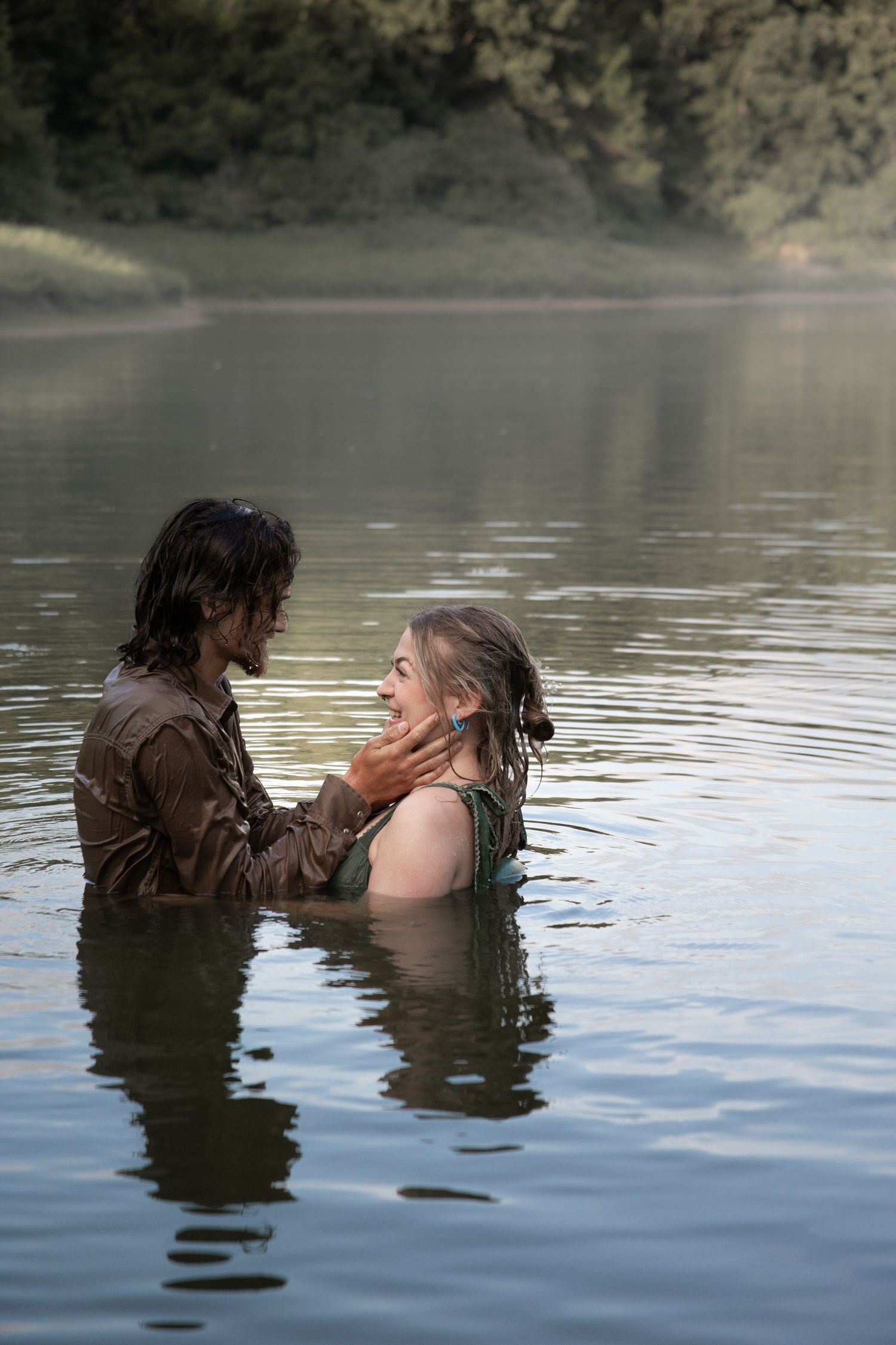 Couple embracing while standing waist-deep in misty lake water.