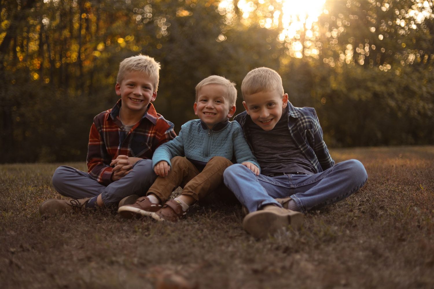 Group relaxing on ground during sunset photoshoot in wooded area.
