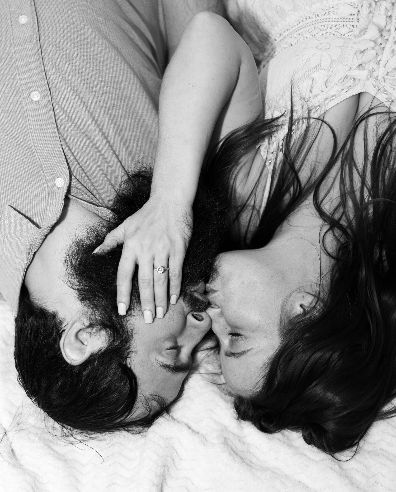 An artistic black and white photo of a couple lying close together.