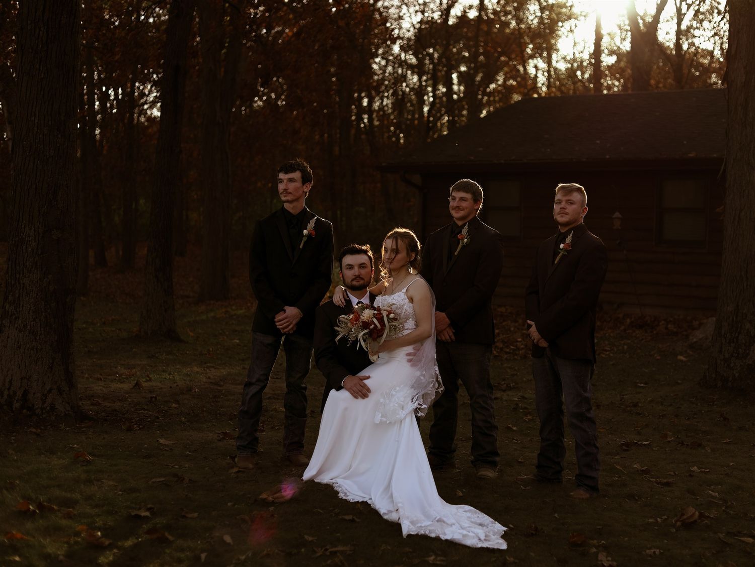 Wedding party gathered in a wooded setting during golden hour.