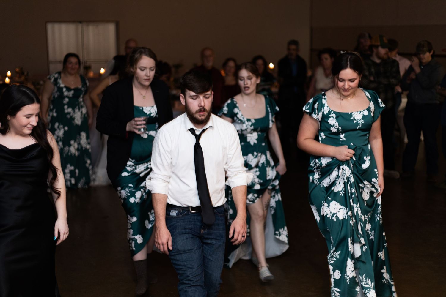 People dancing in a dark room wearing teal and white outfits at what appears to be a social gathering.