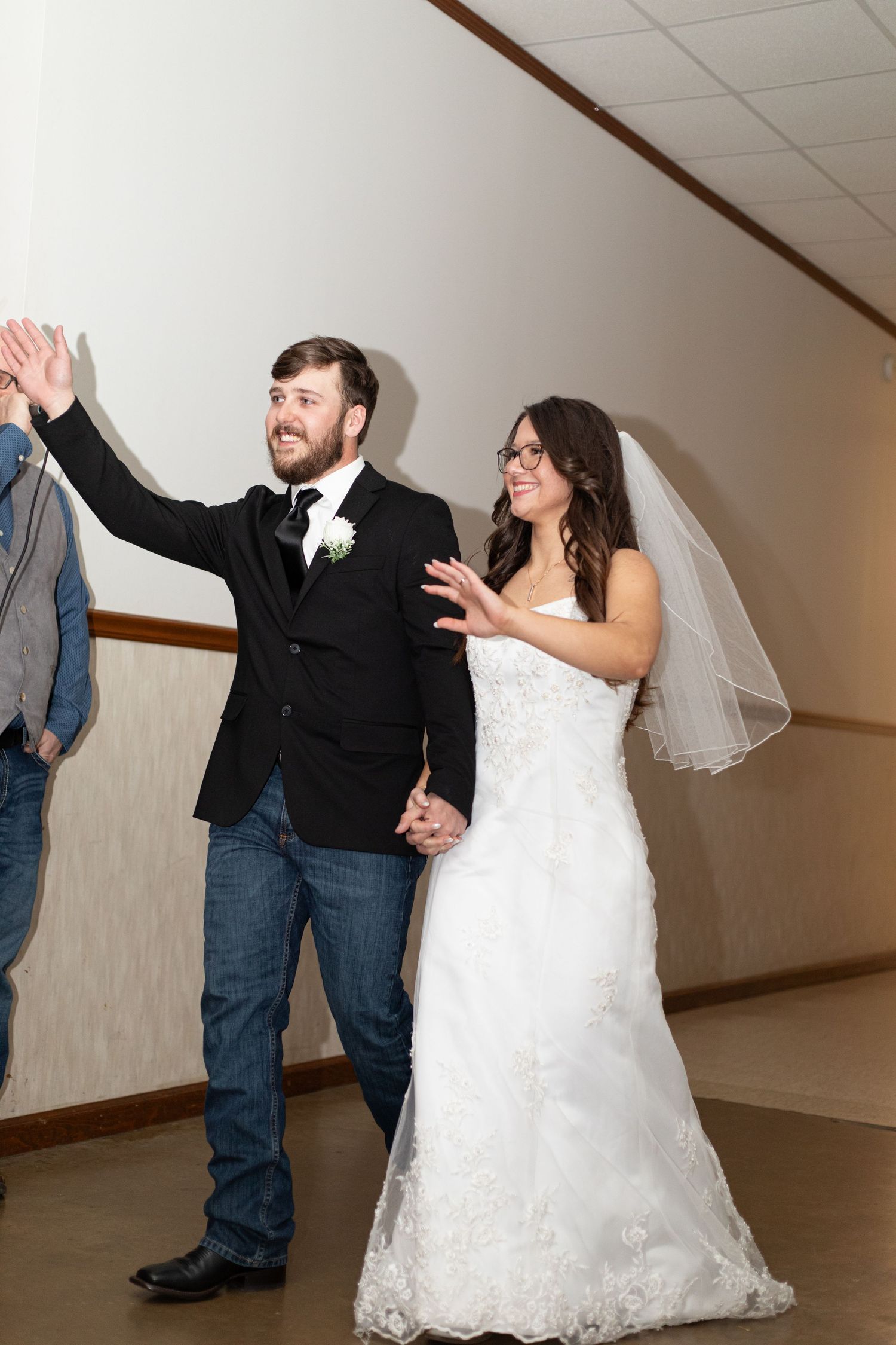 A couple performs a fun dance sequence at their wedding reception, showing joyful movement in formal attire.