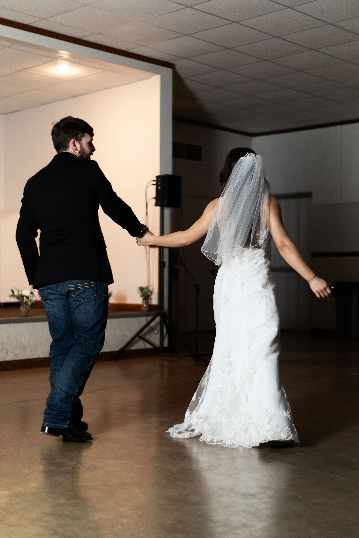 A couple dancing together at their wedding reception, with the bride in a white gown and flowing veil.