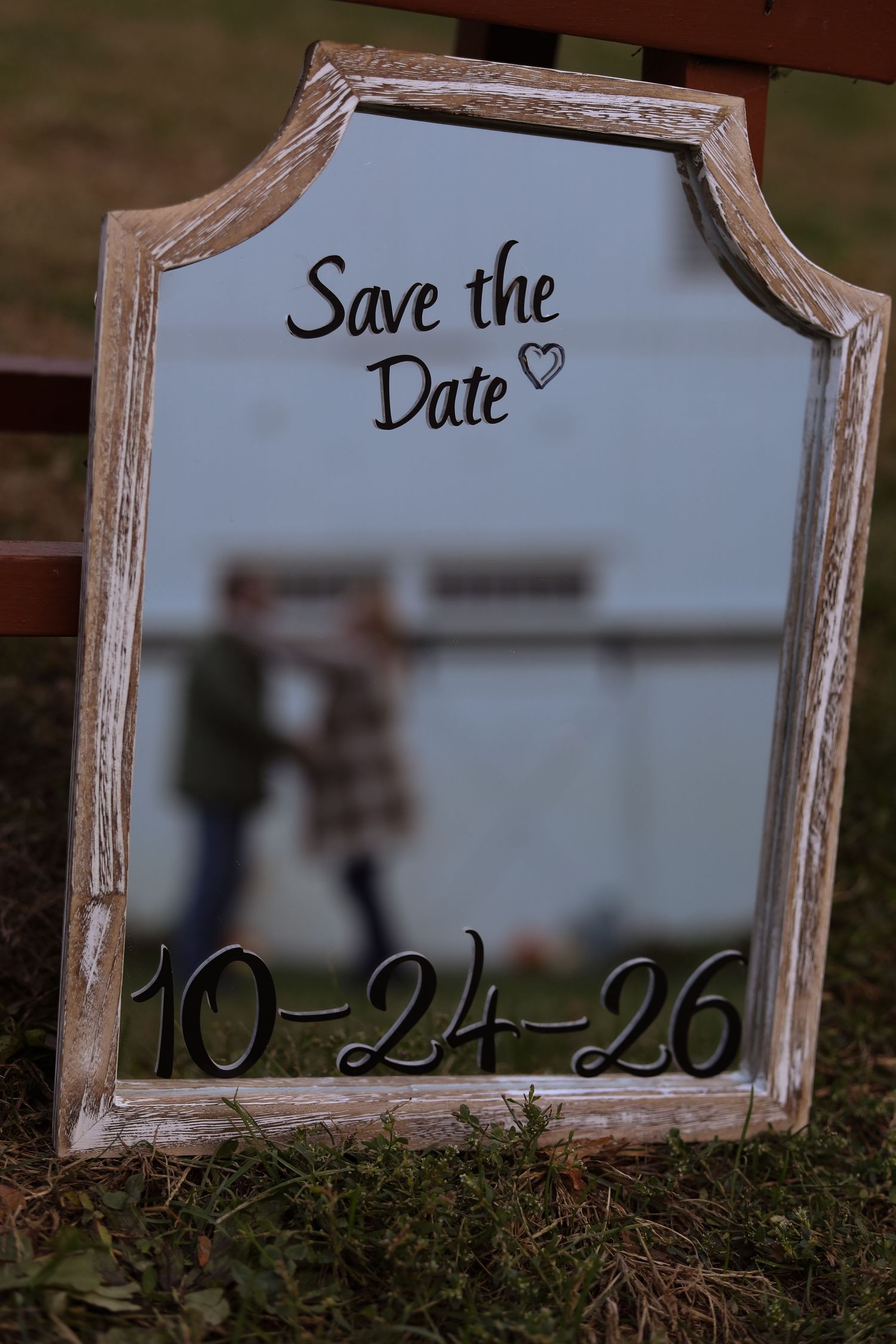 A rustic framed save-the-date sign with wedding details written in elegant script.