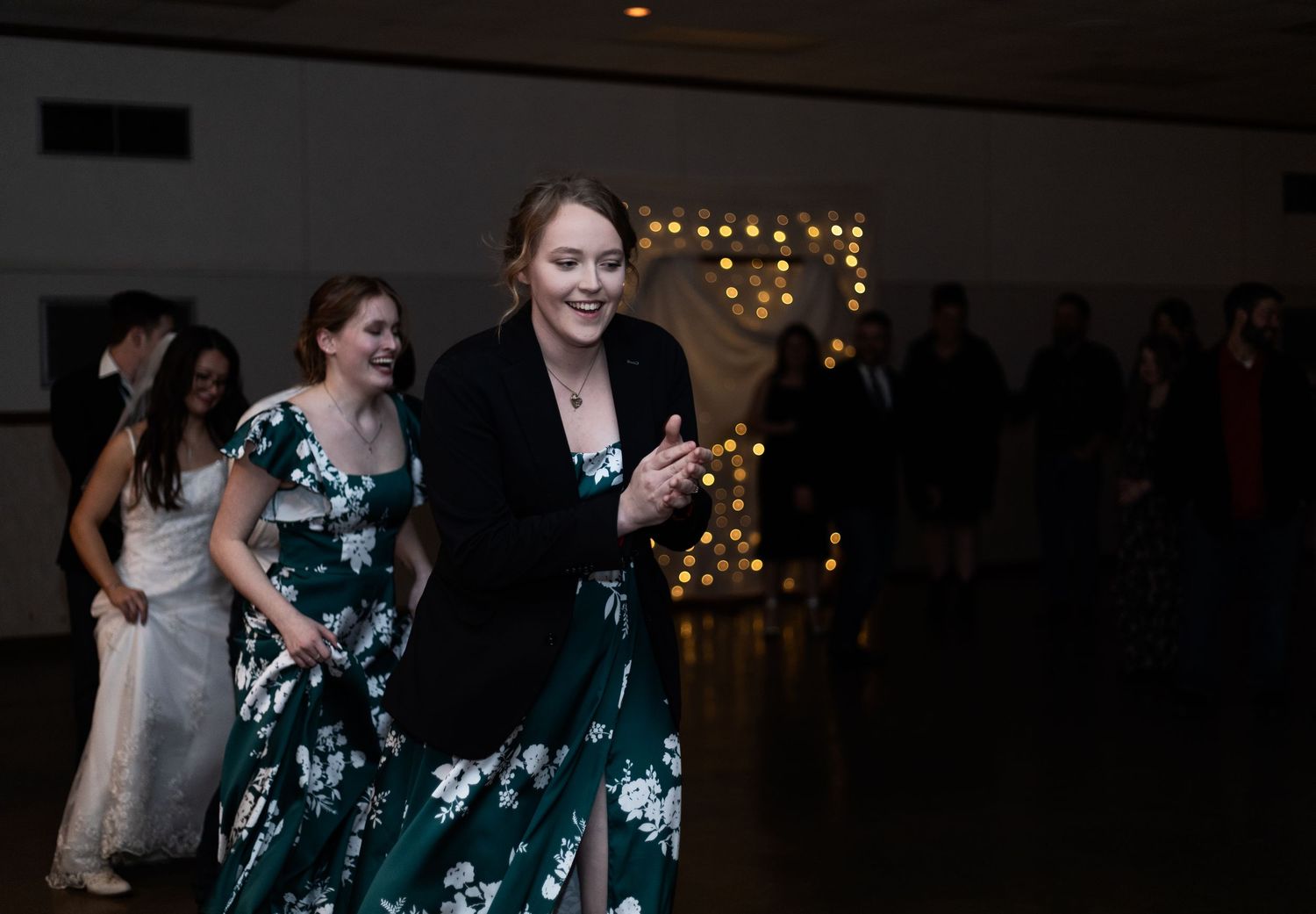 People dancing and having fun at an evening event with twinkle lights glowing in the background.