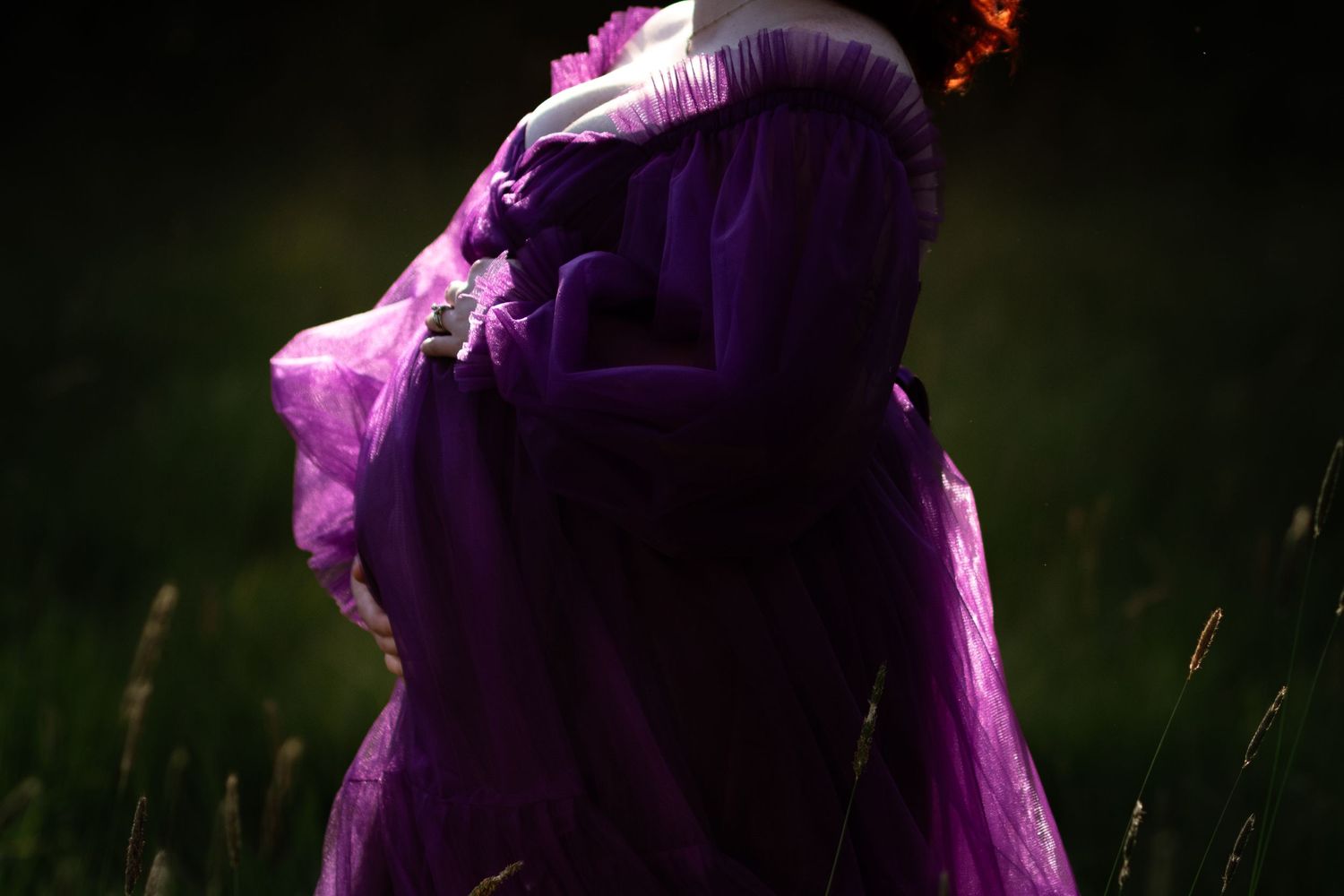 A figure in a flowing purple gown stands in a dark field, with a flame glowing above their head.