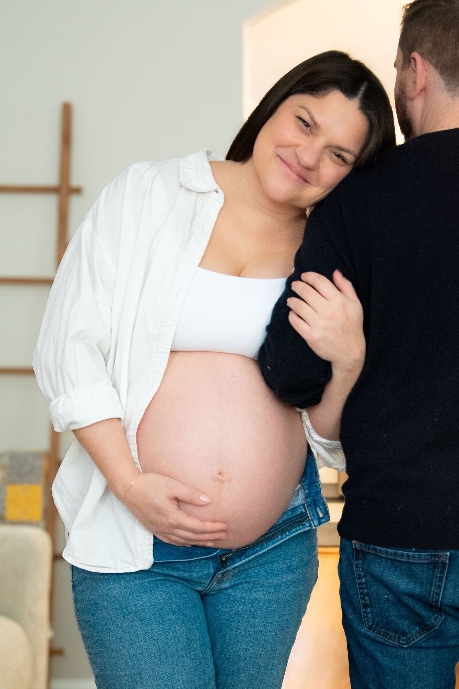 A series of photos showing a pregnant belly in jeans and white top in casual indoor setting.