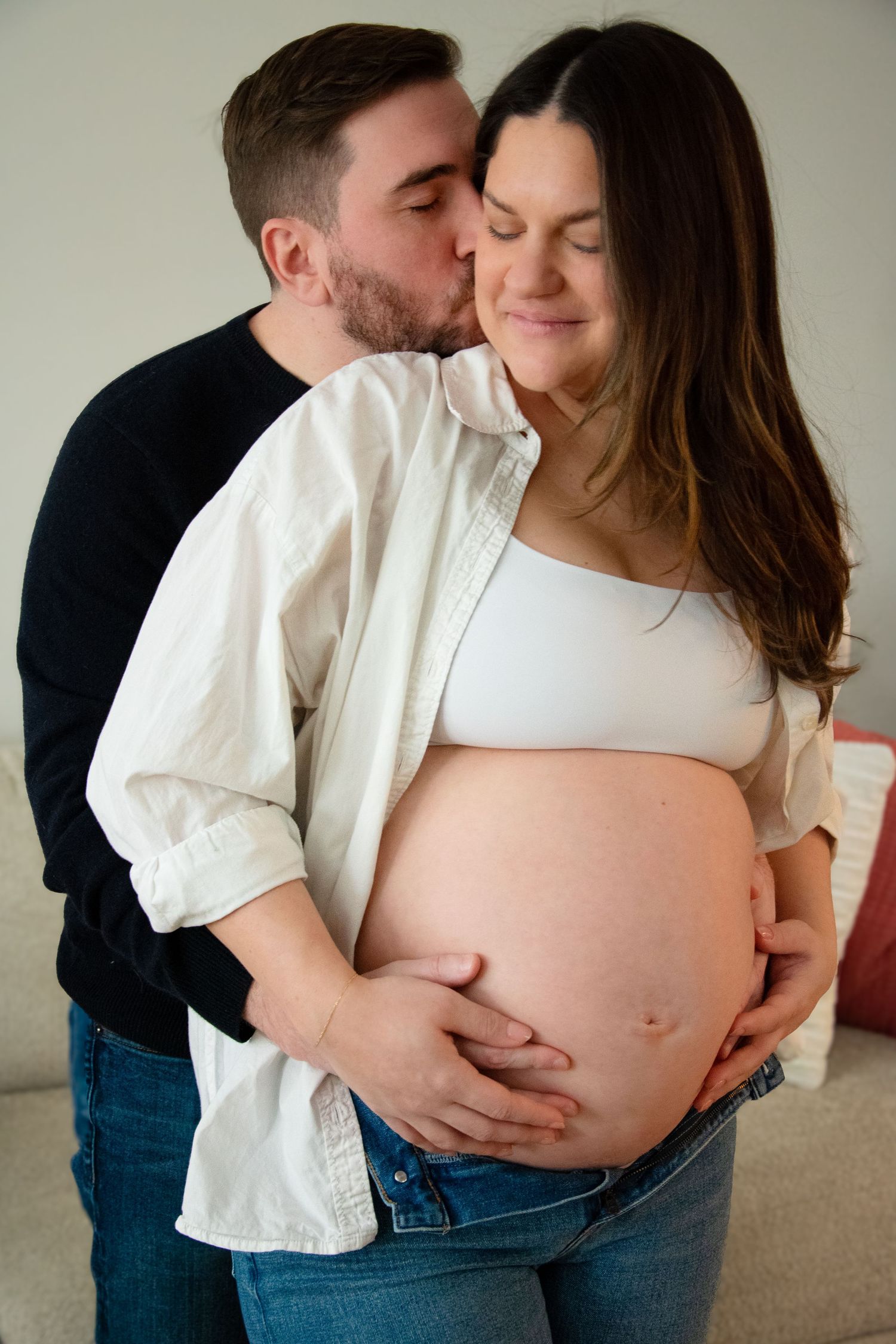 Intimate maternity portraits of couple in white and black clothing.