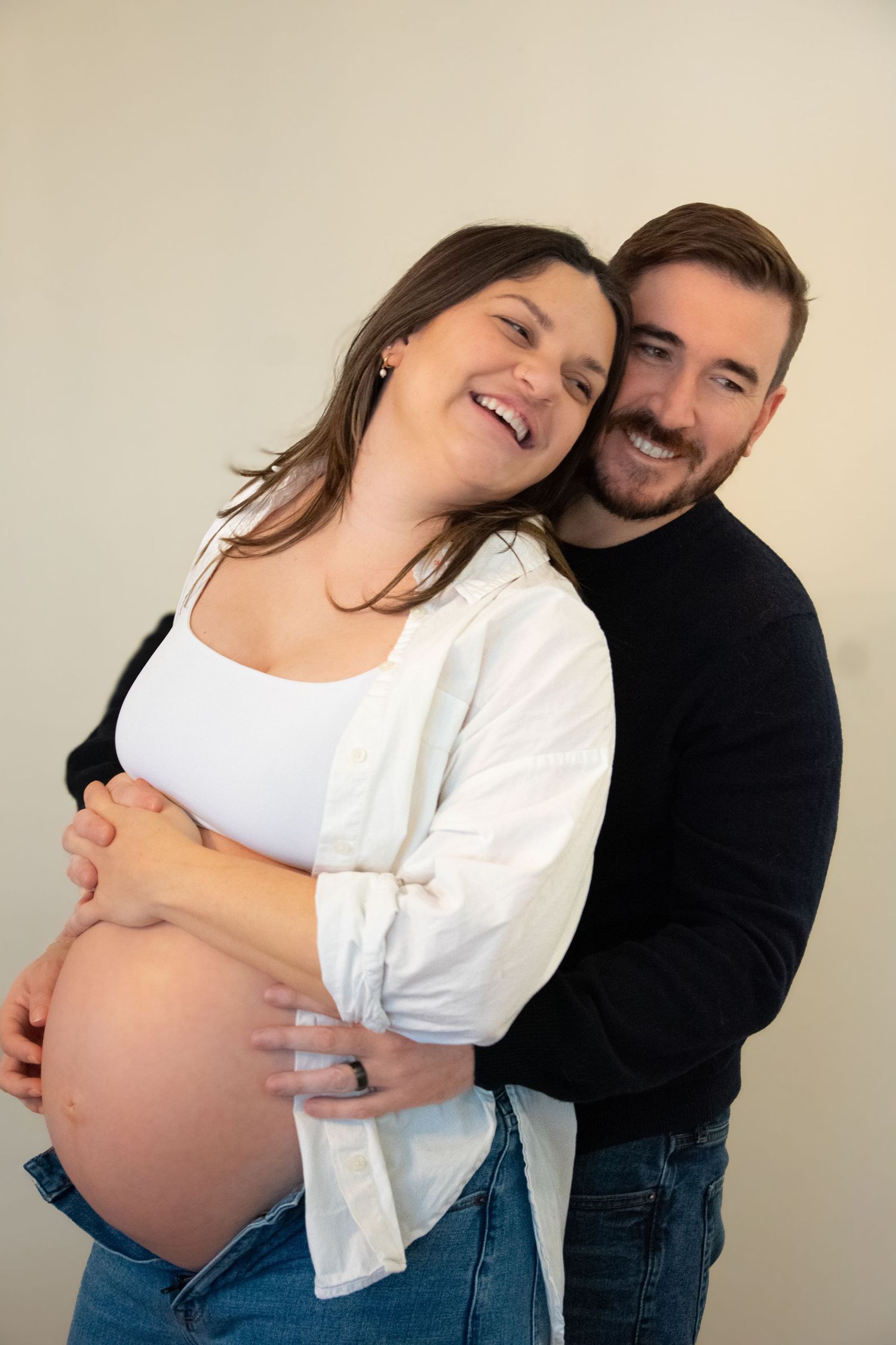 Maternity photo series showing expecting couple embracing in casual attire.