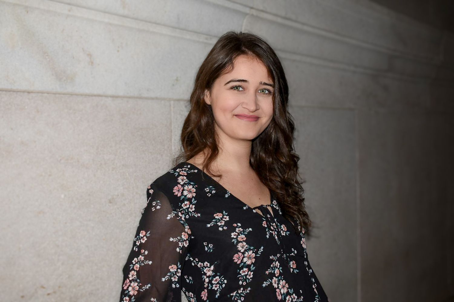 Woman in black and white floral dress poses at night for portraits against a marble wall in DC. Professional portrait photography
