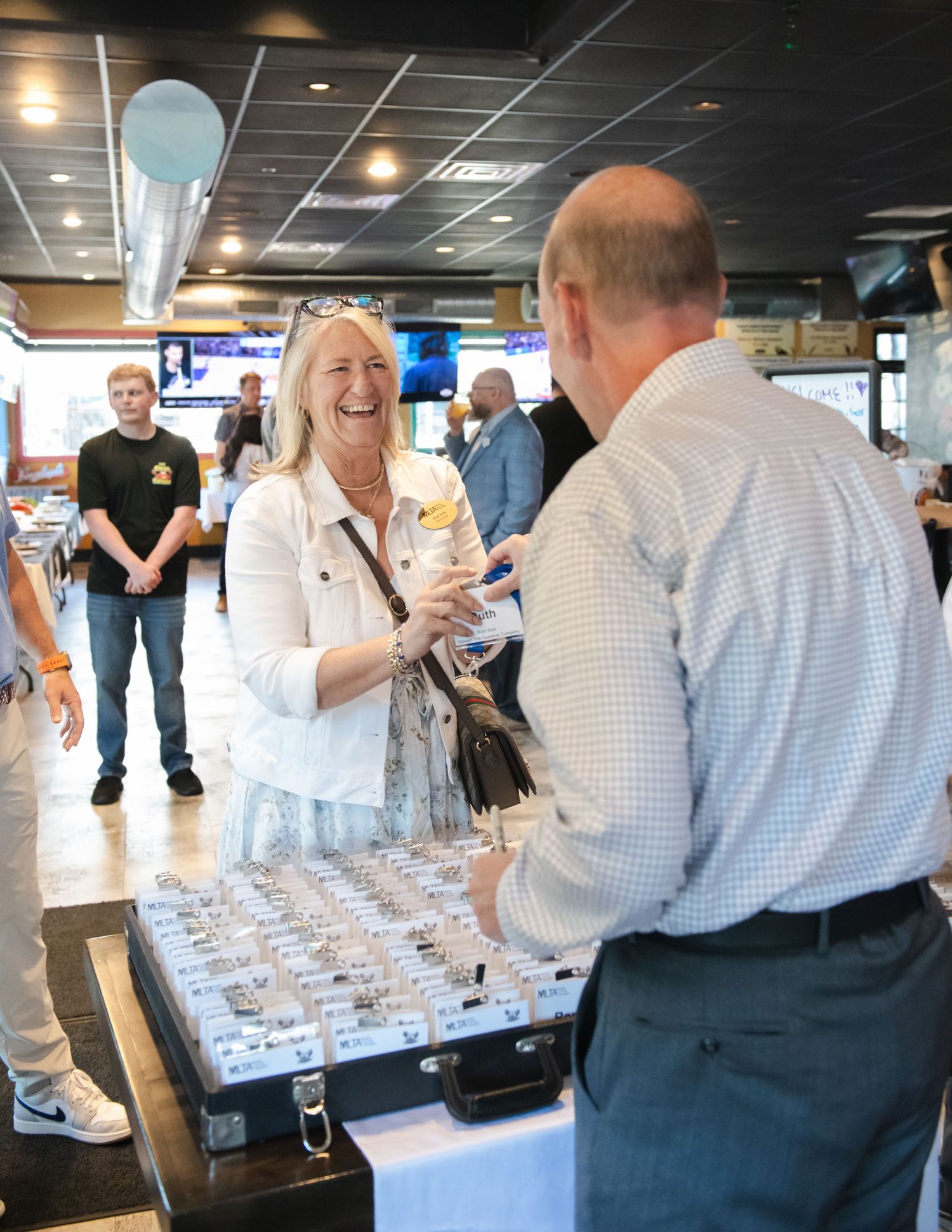 Woman laughing joyfully while receiving an award at an indoor corporate or community celebration event.