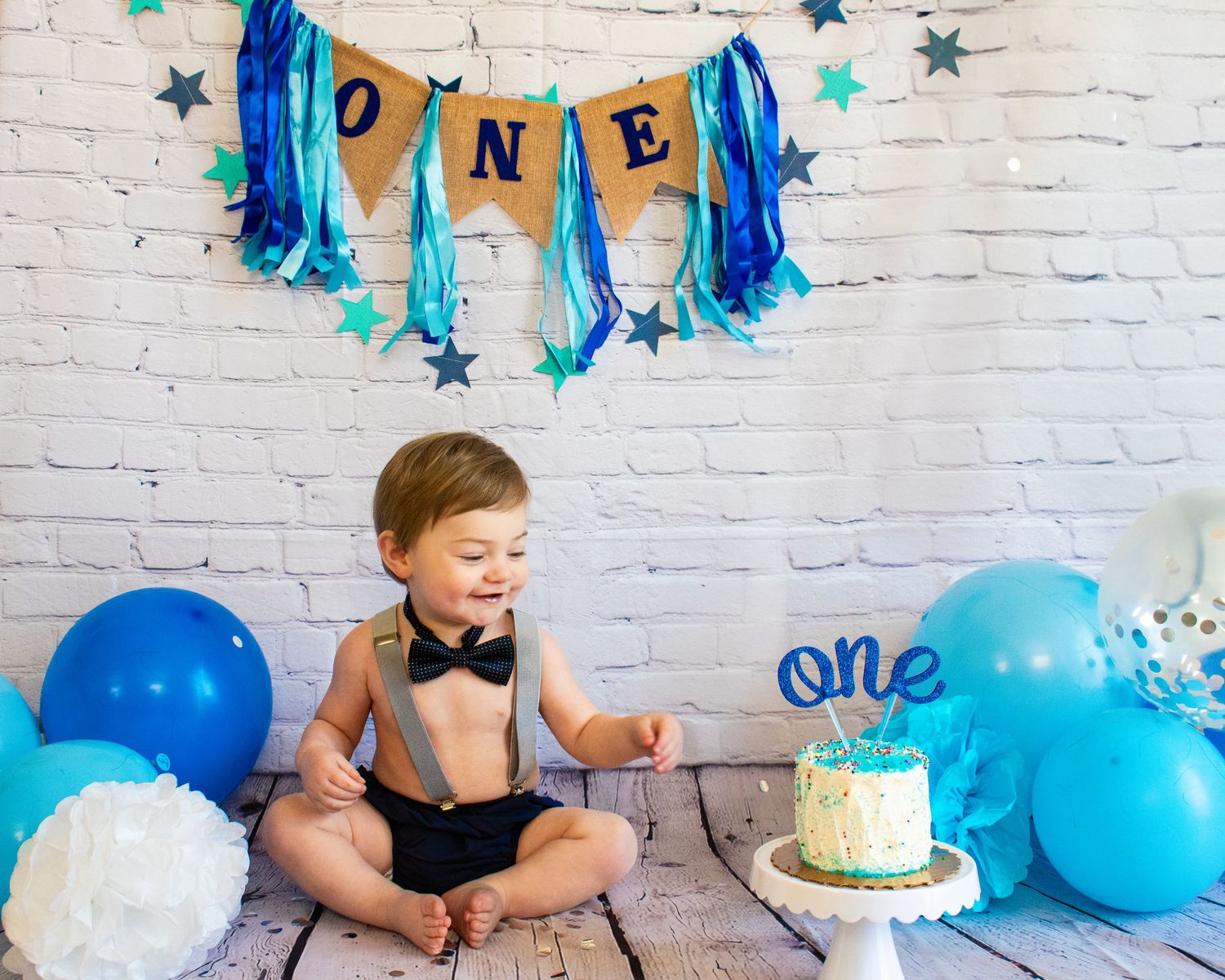 Small boy wearing a bow tie and suspenders under a blue banner that reads 