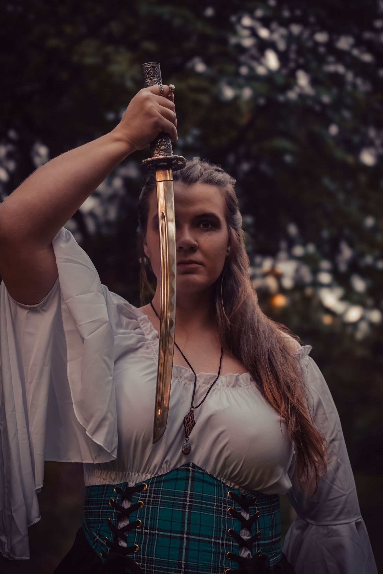 A person in a white blouse and plaid skirt holds up an antique lantern in a mystical forest setting.