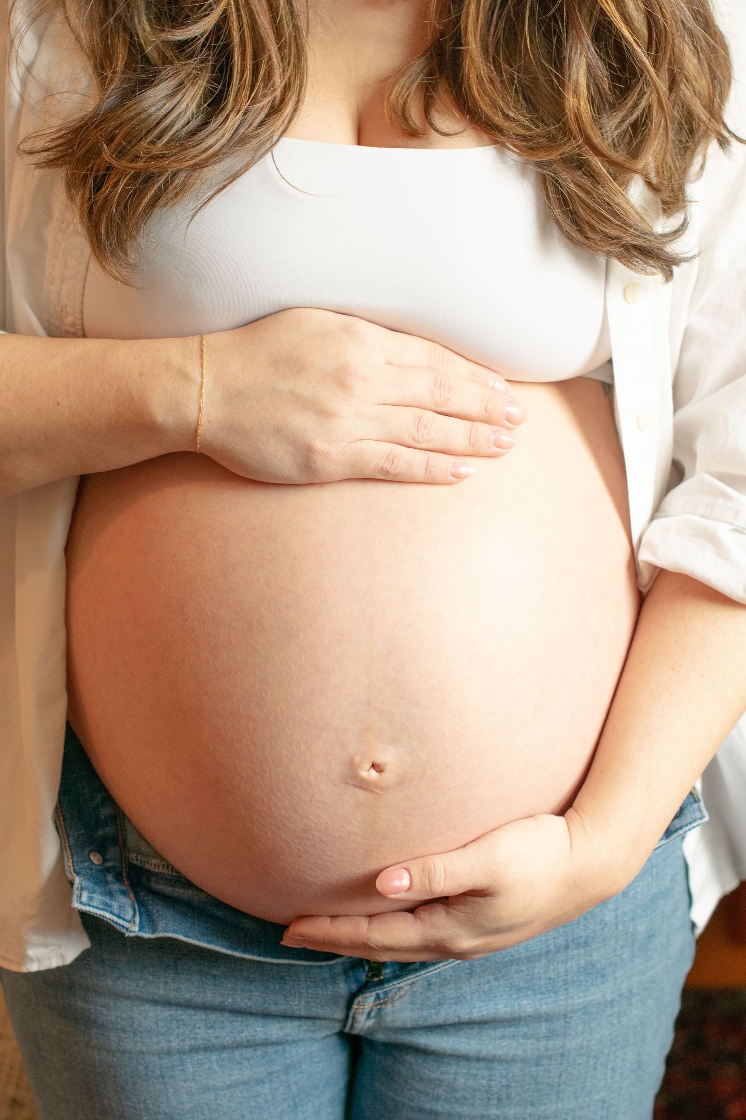 Progressive photos showing a growing pregnant belly against casual denim and white clothing.