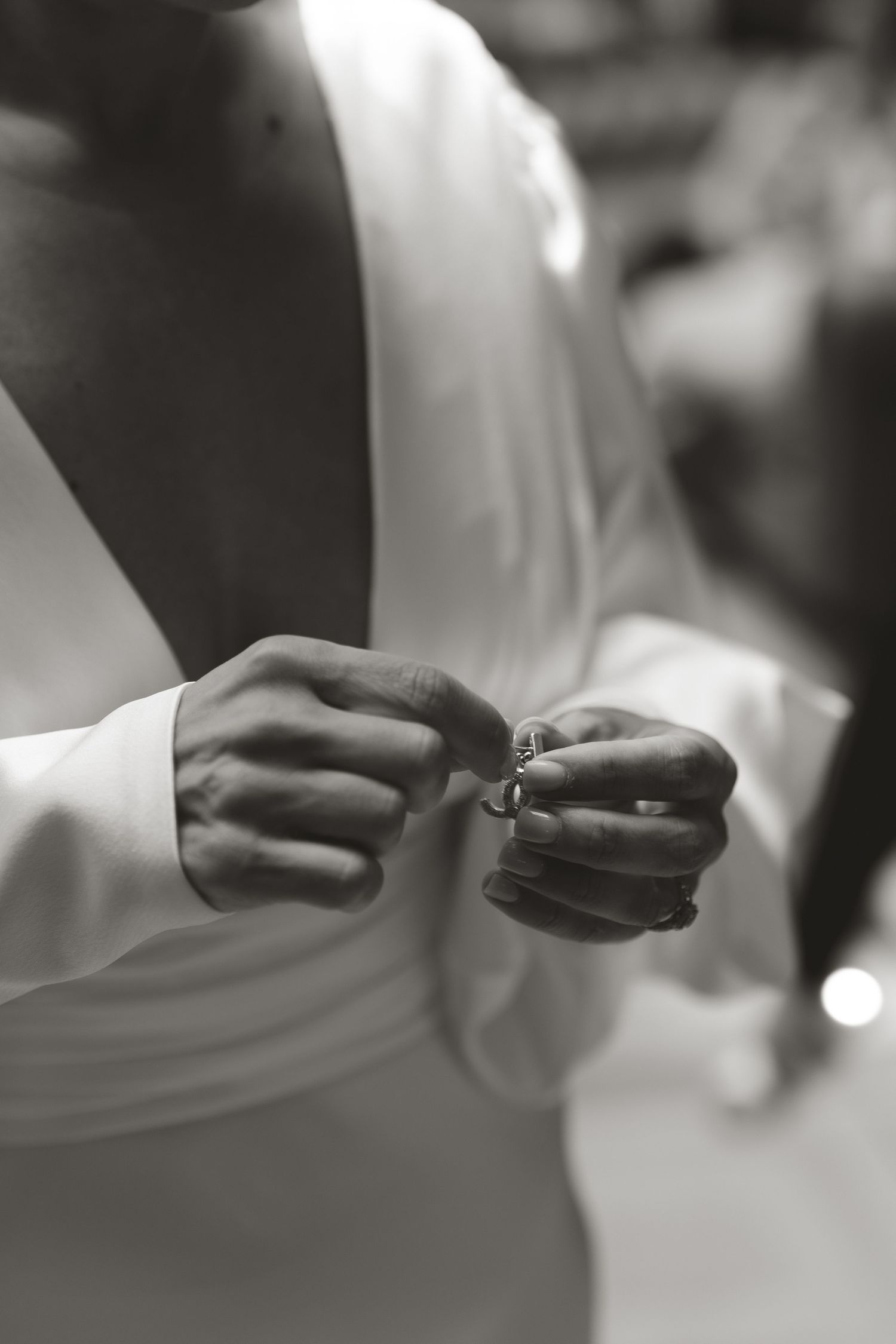 A sequence of black and white close-up shots showing hands exchanging wedding rings during a ceremony.