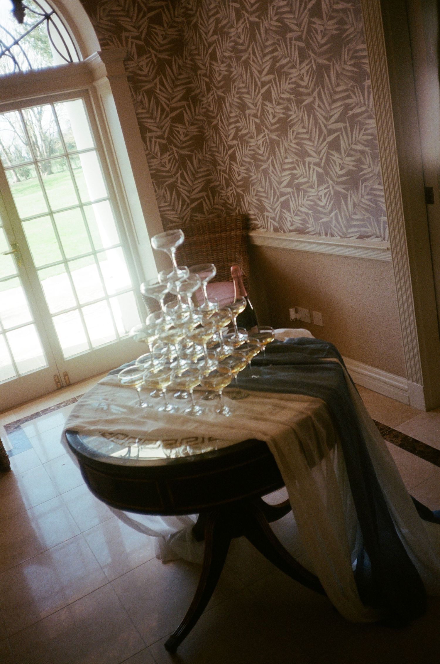 A series of four photos showing champagne glasses arranged on a dark wooden table near a window with natural light.