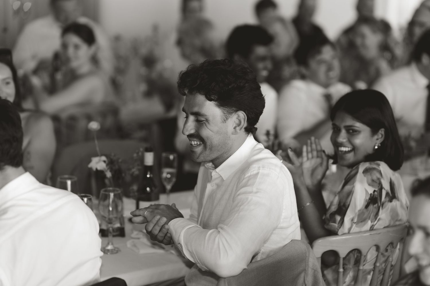 Wedding guests react with laughter and joy during reception speeches.