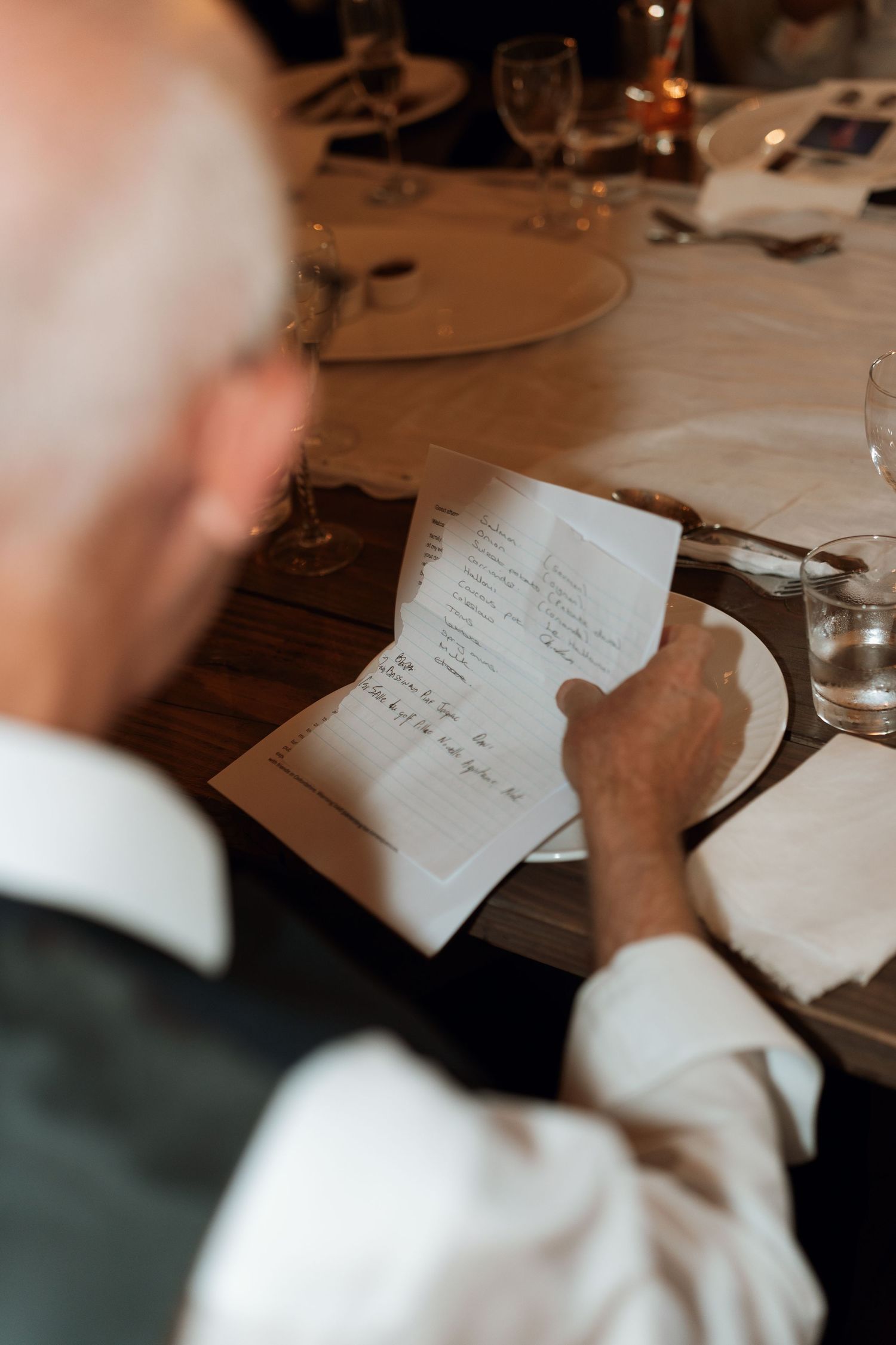 Close-up shot of someone writing heartfelt notes at a wedding reception table.