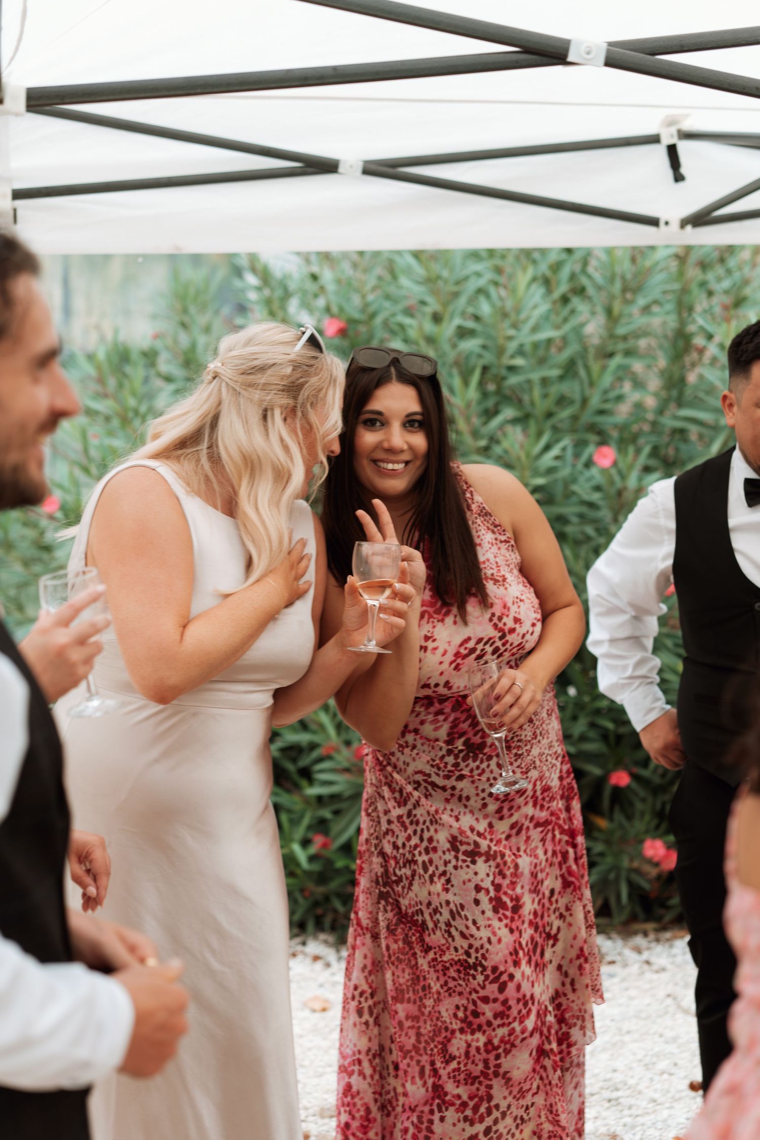 Wedding guests in white and red dresses dancing and celebrating outdoors.