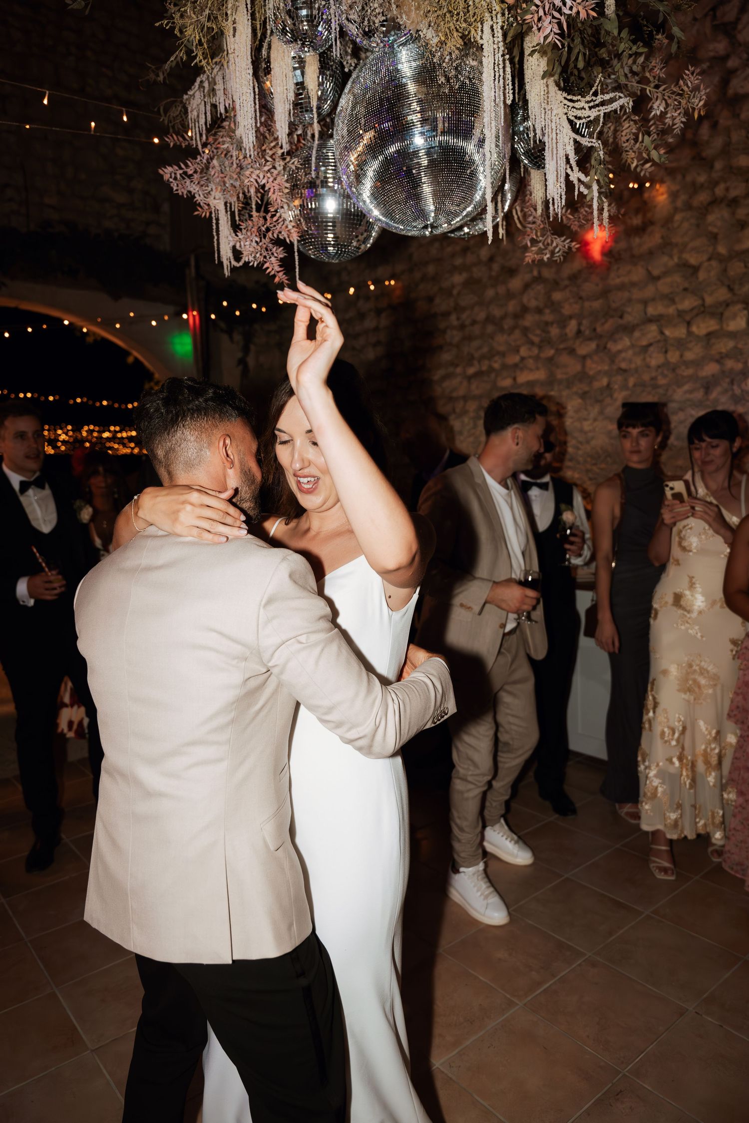 Wedding reception dance floor with string lights and disco ball creating a festive atmosphere.