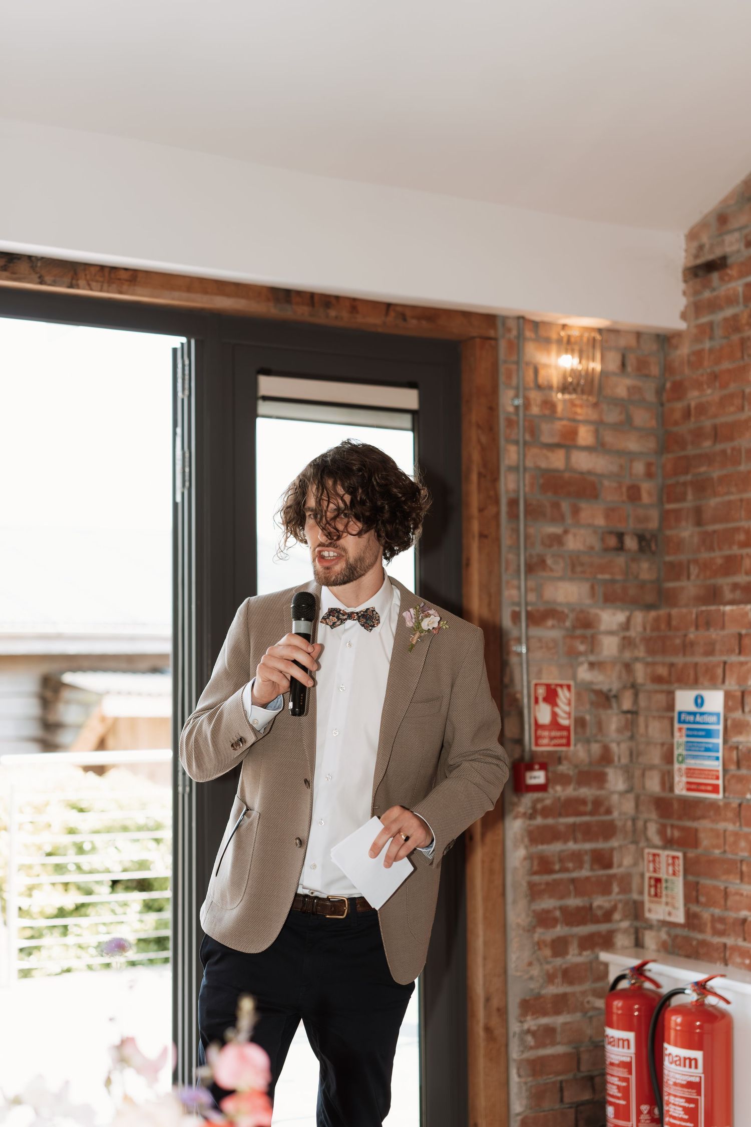 Wedding speech being given in an industrial-style venue with exposed brick walls.