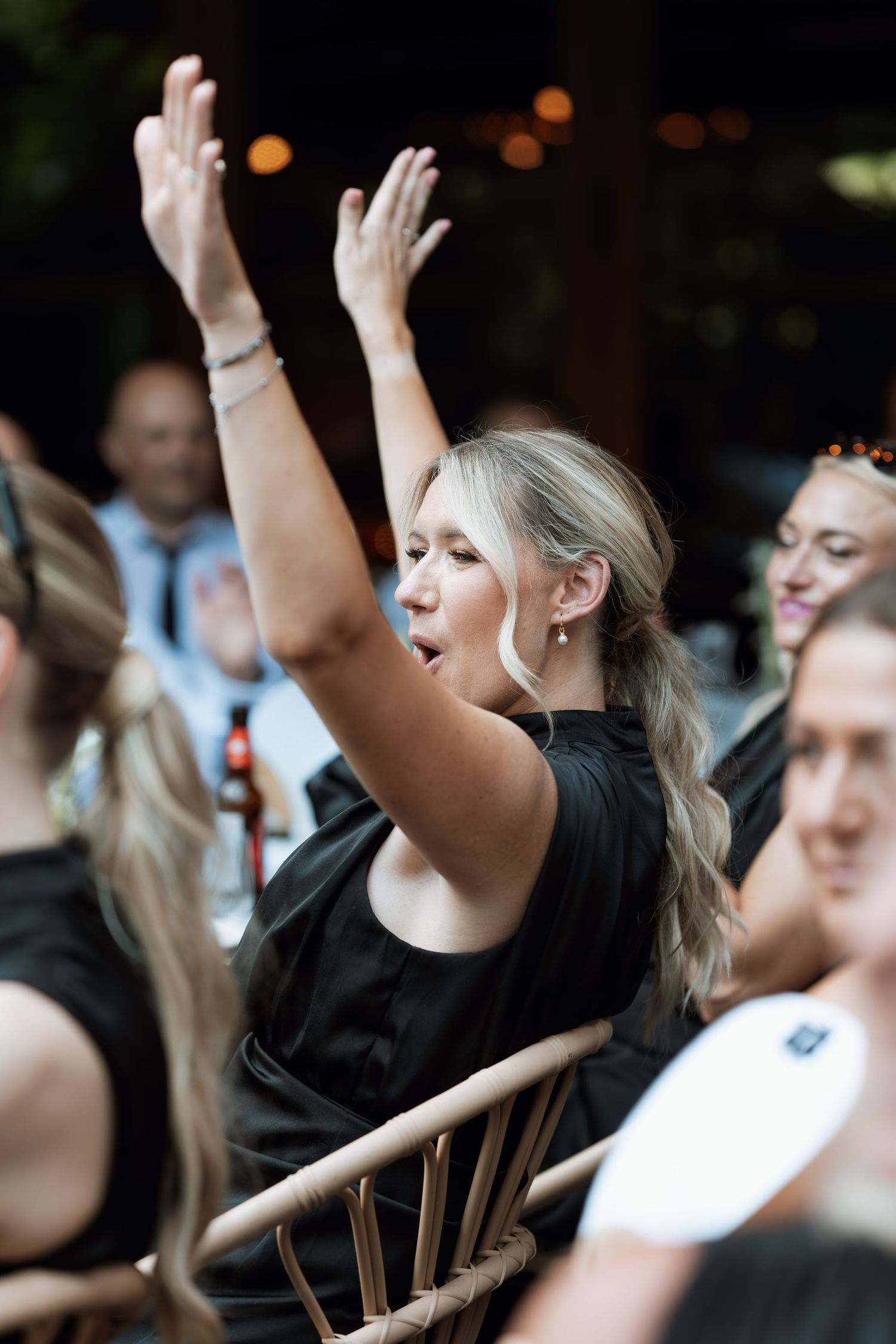 People with raised hands during an energetic celebration event, wearing black attire.