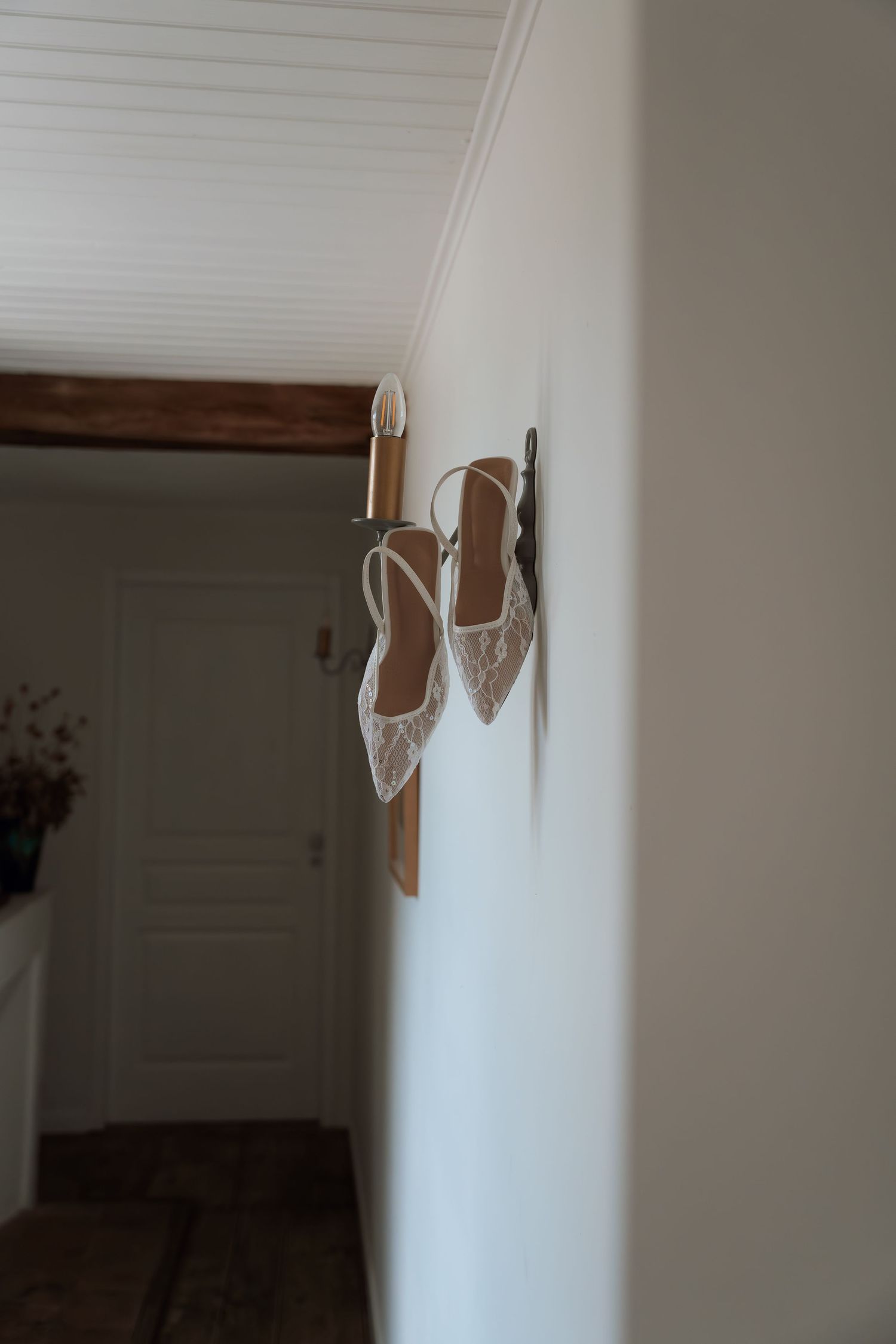 White high heel shoes displayed on a wall shelf in a home interior.